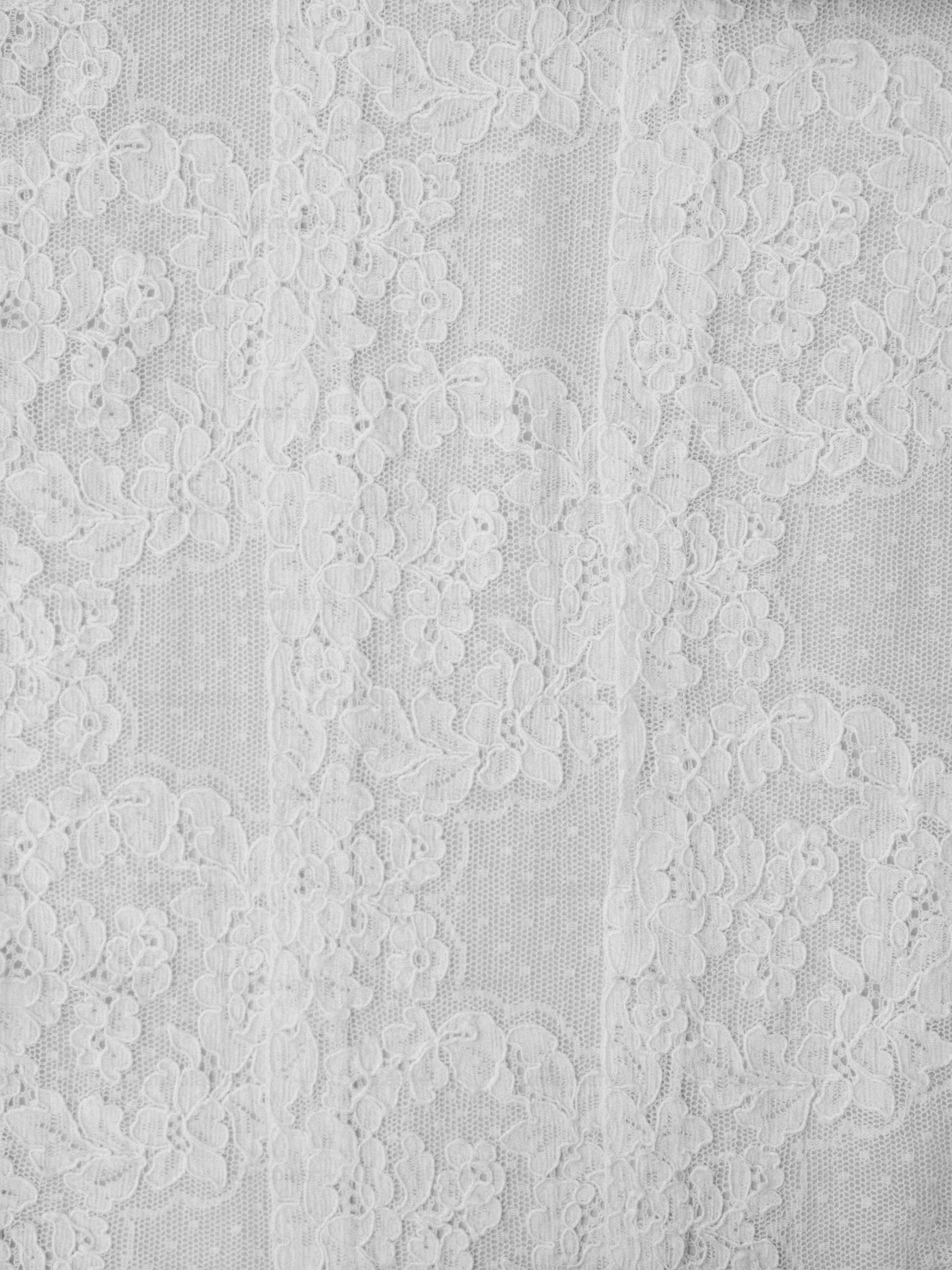 Close-up of white lace fabric with floral patterns.