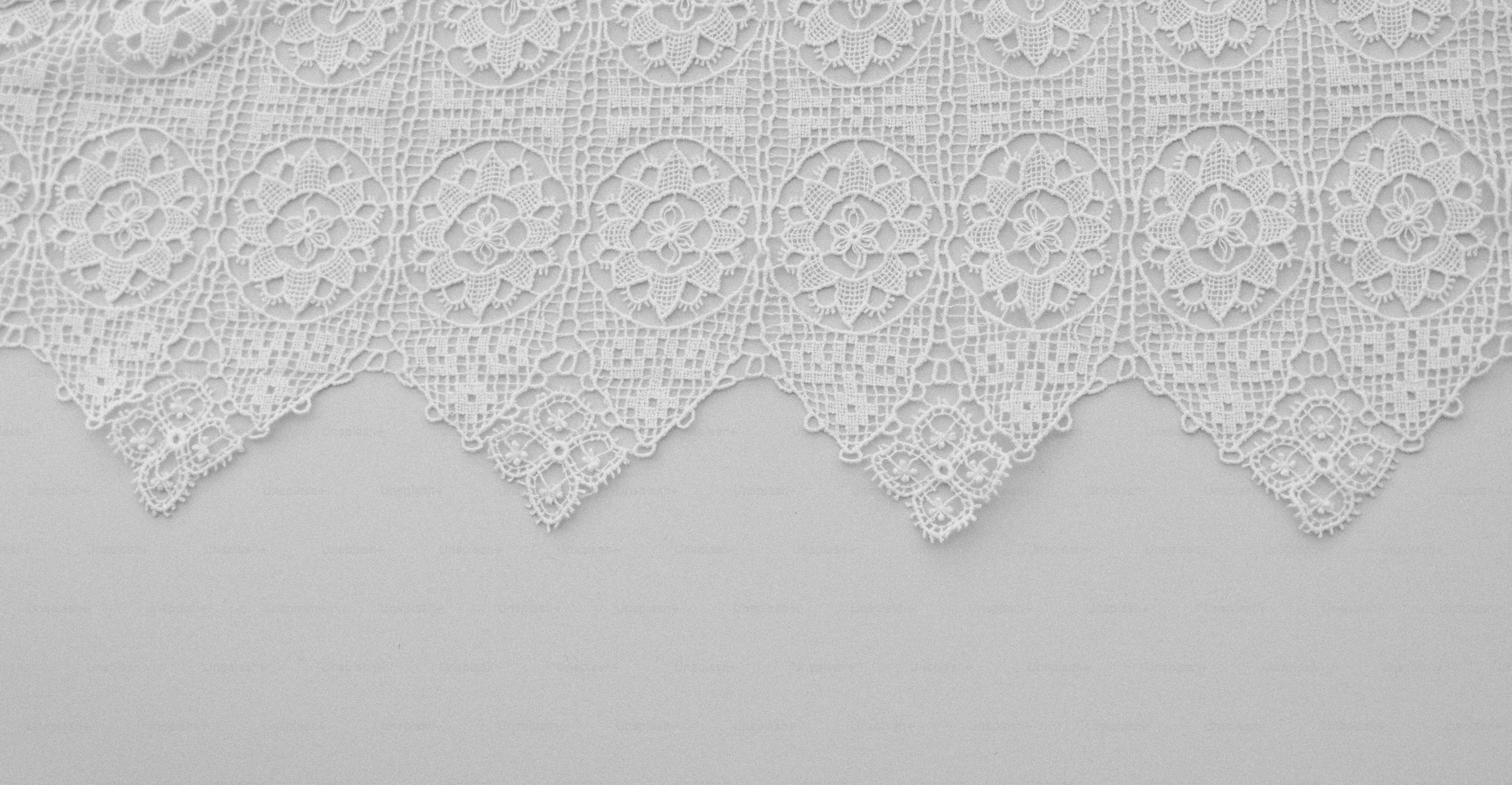 Close-up of white lace fabric with intricate patterns.