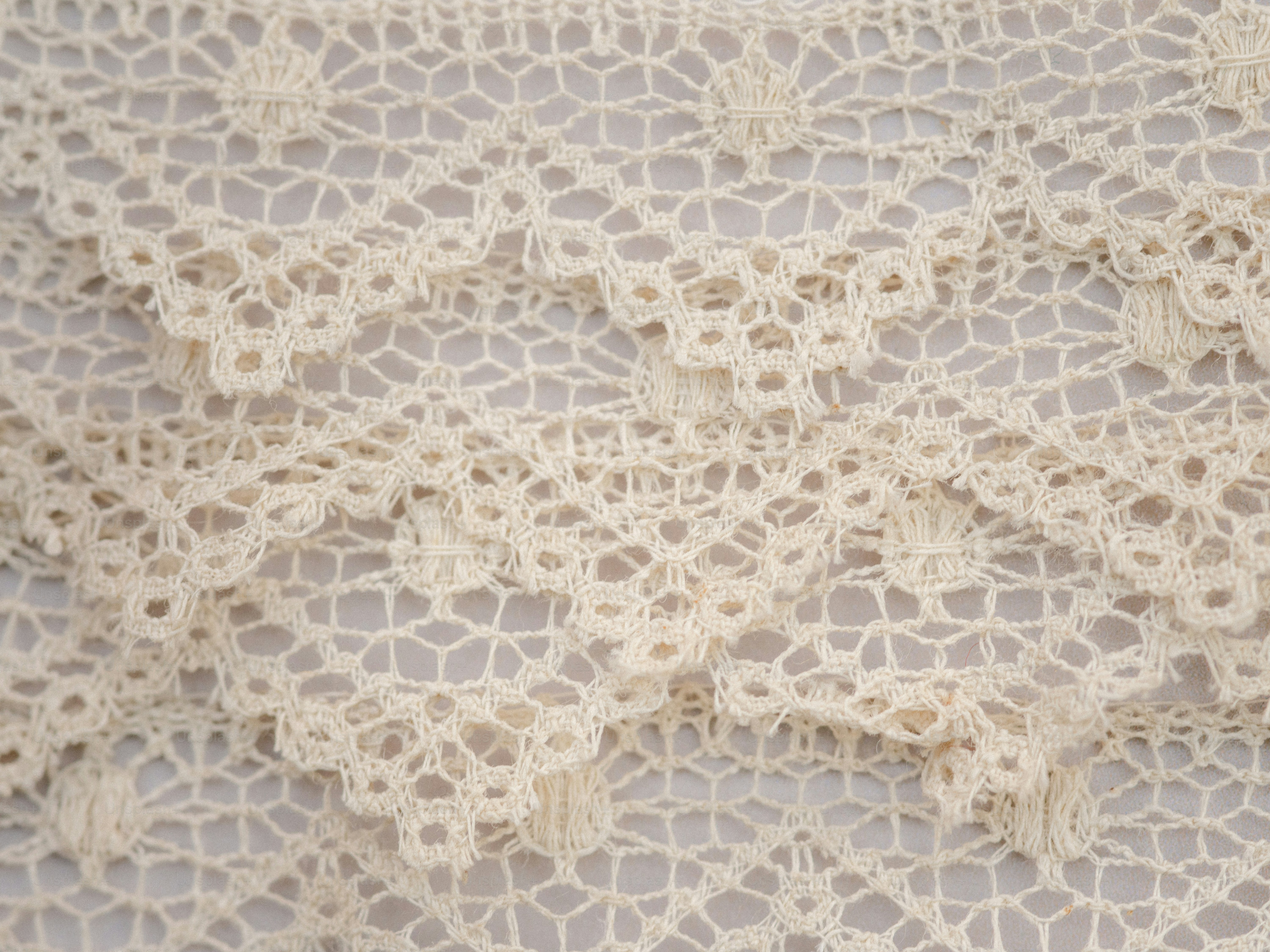Delicate cream-colored lace fabric with intricate patterns