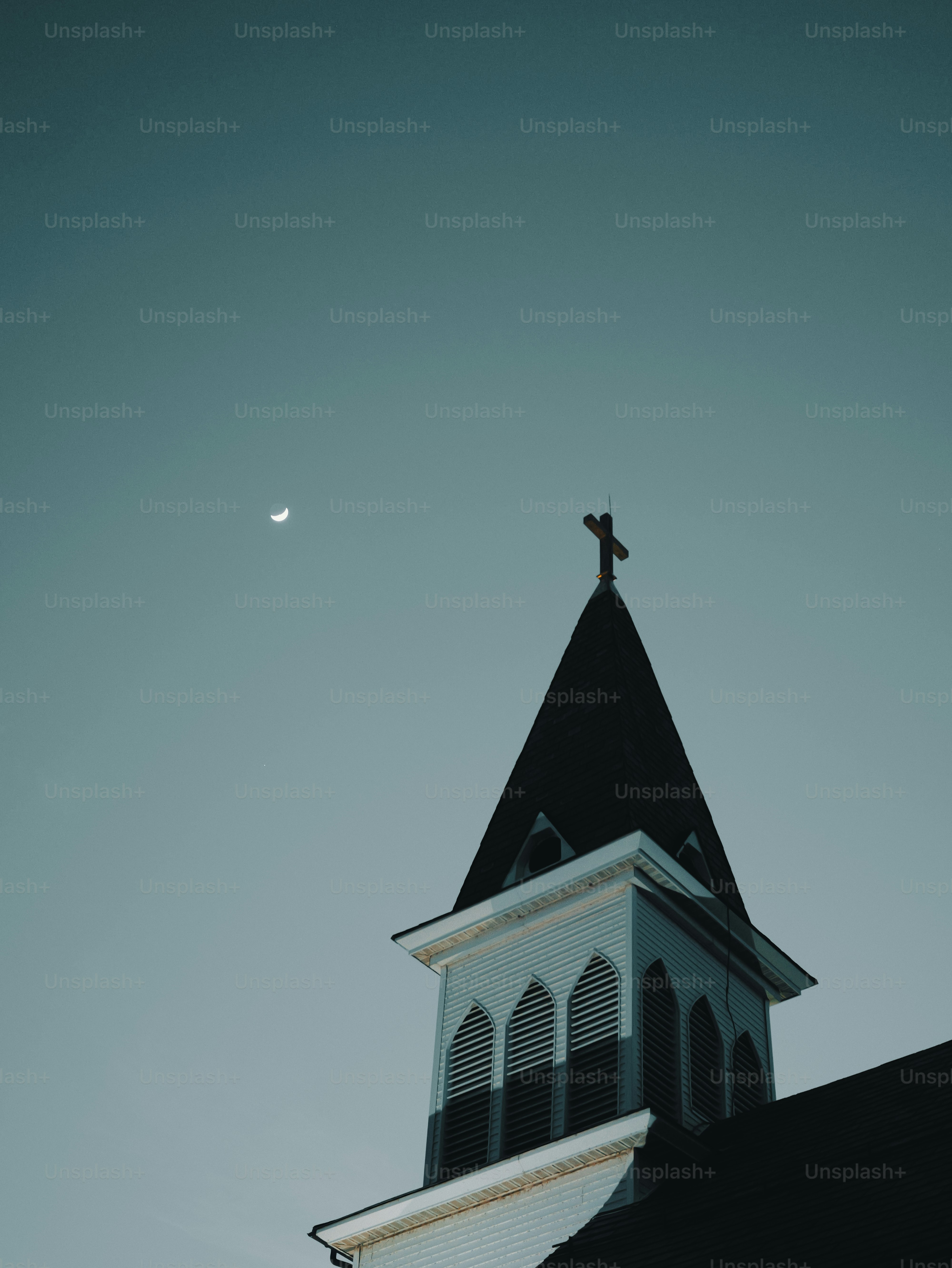 Church steeple with cross against a twilight sky.
