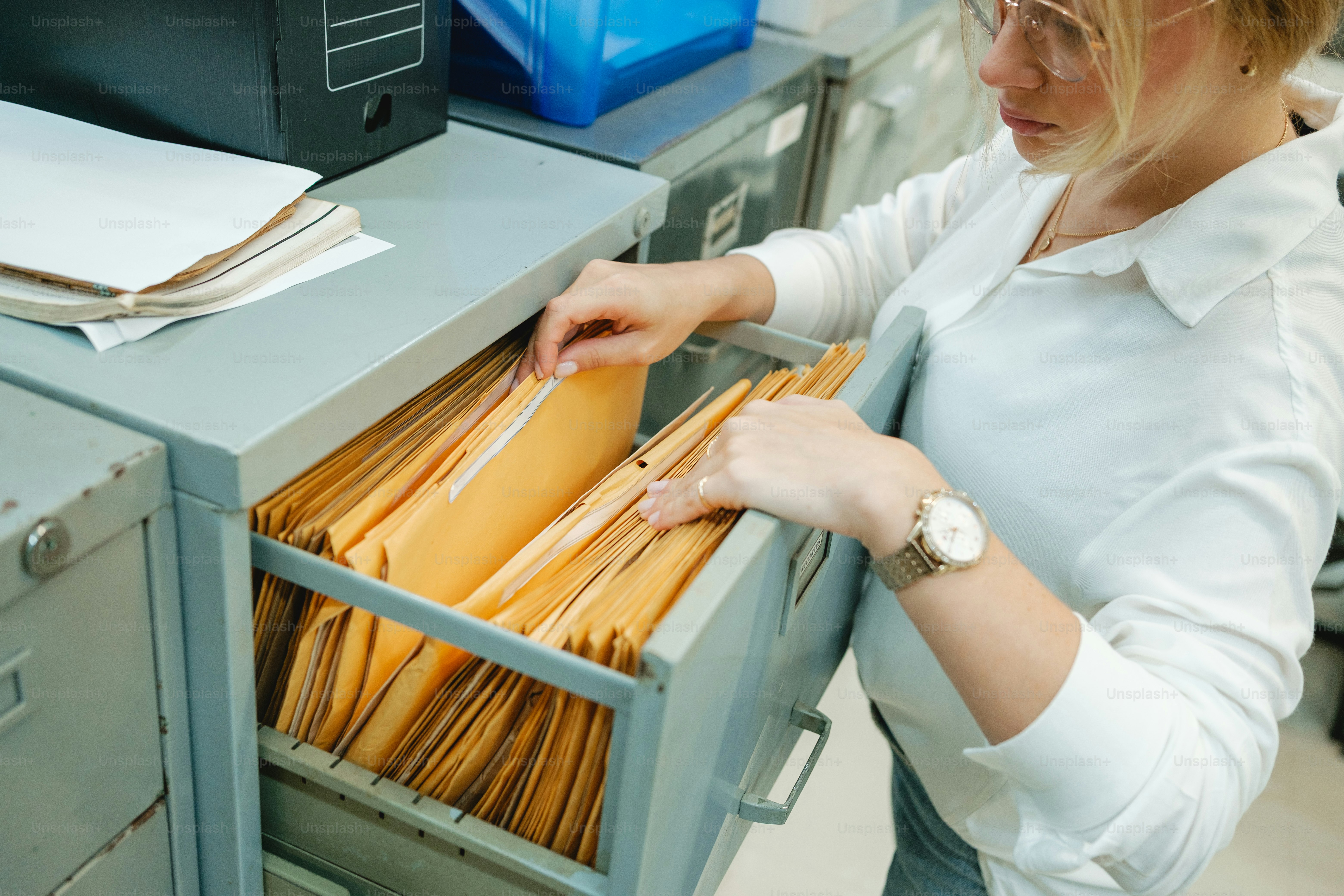 Woman searching through files in a filing cabinet. photo – Documents ...