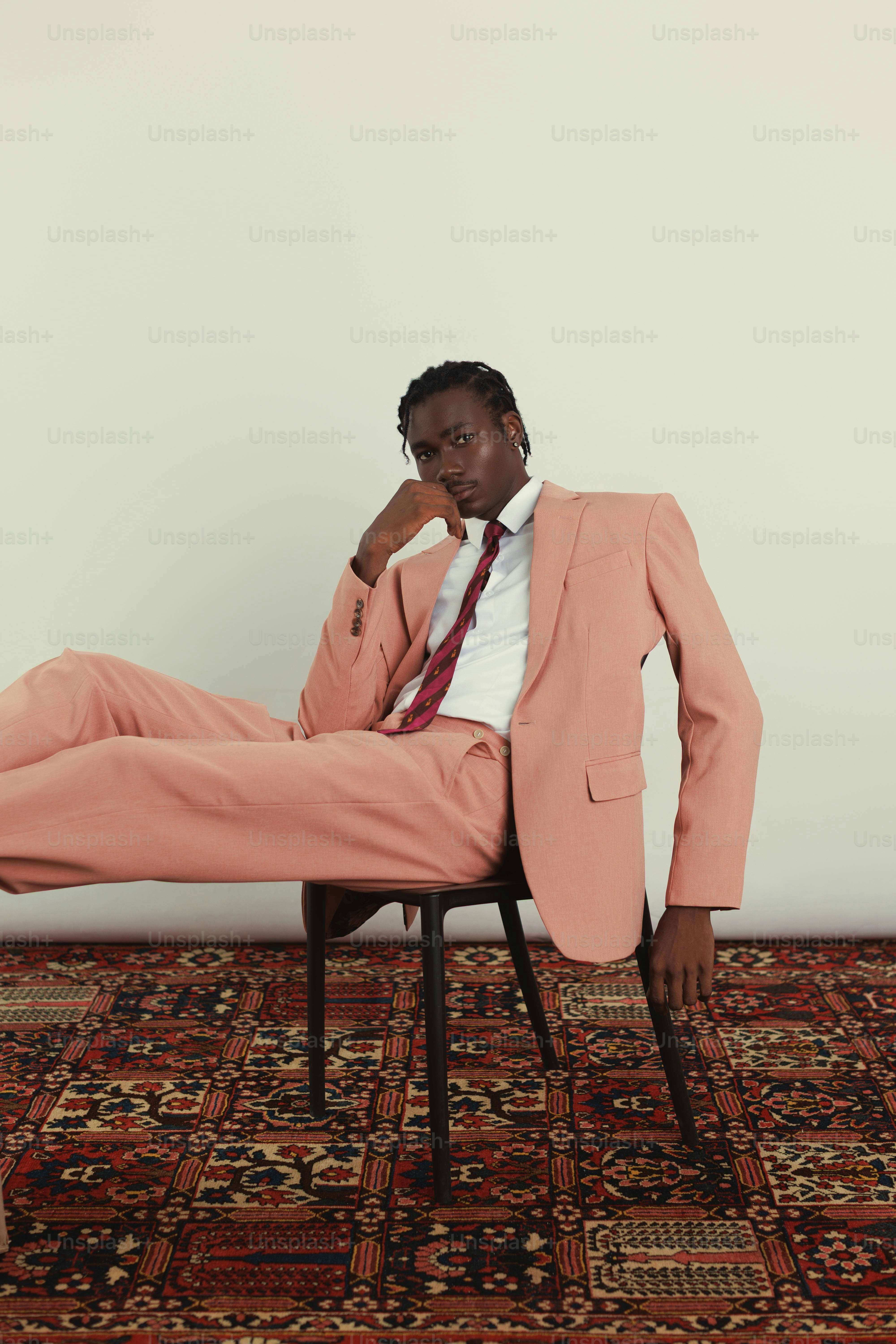 Ein Mann im Pfirsichanzug sitzt auf einem Hocker.