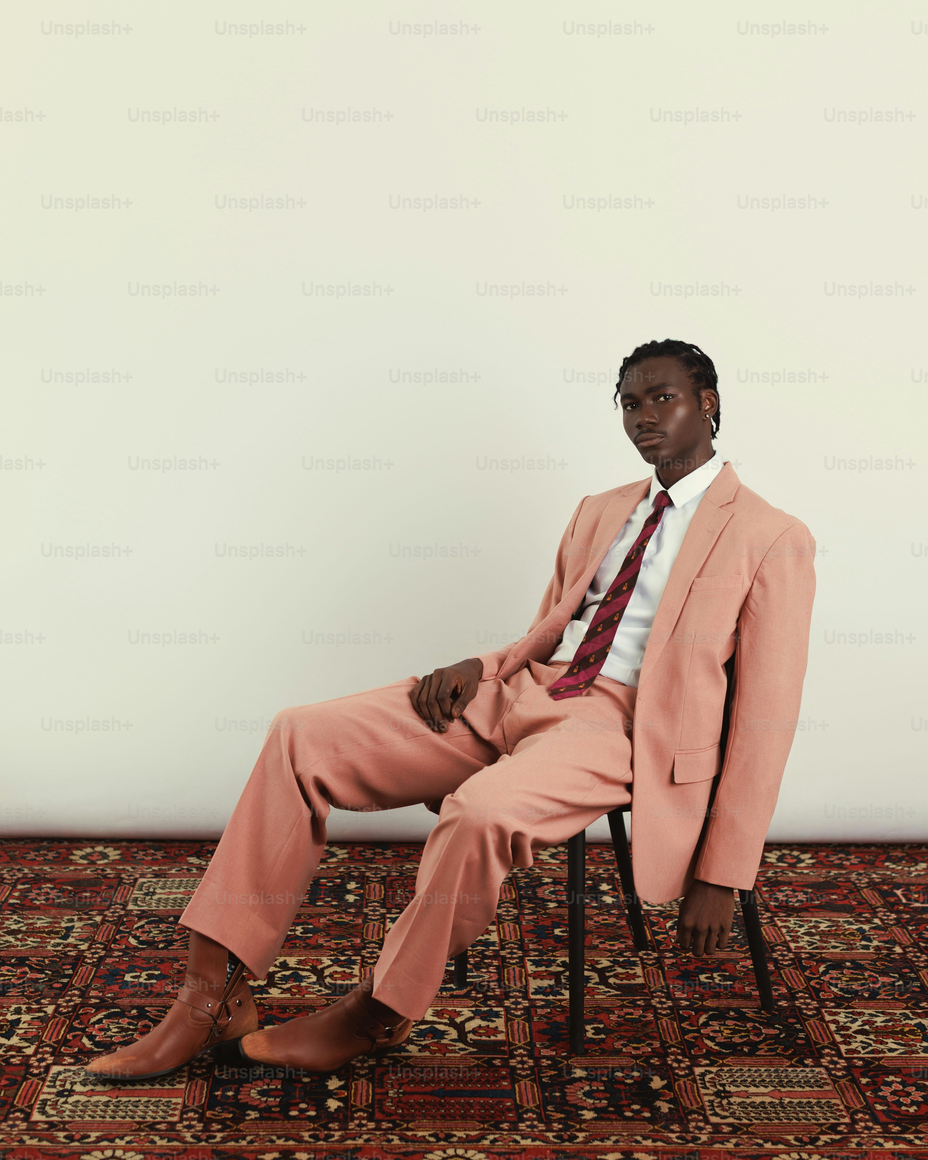 Man in pink suit sitting on chair on patterned rug