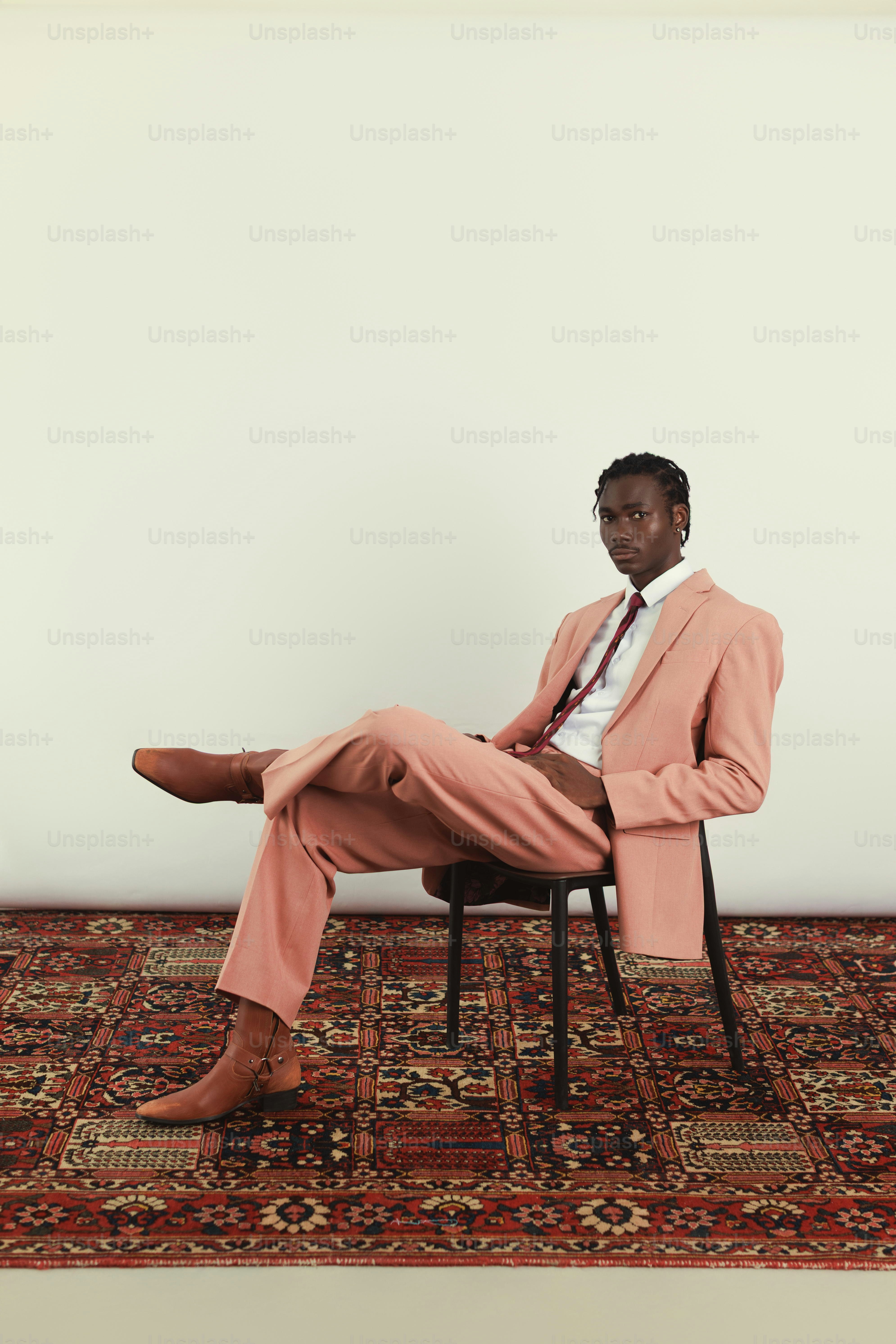 Man in a pink suit sitting on a chair.