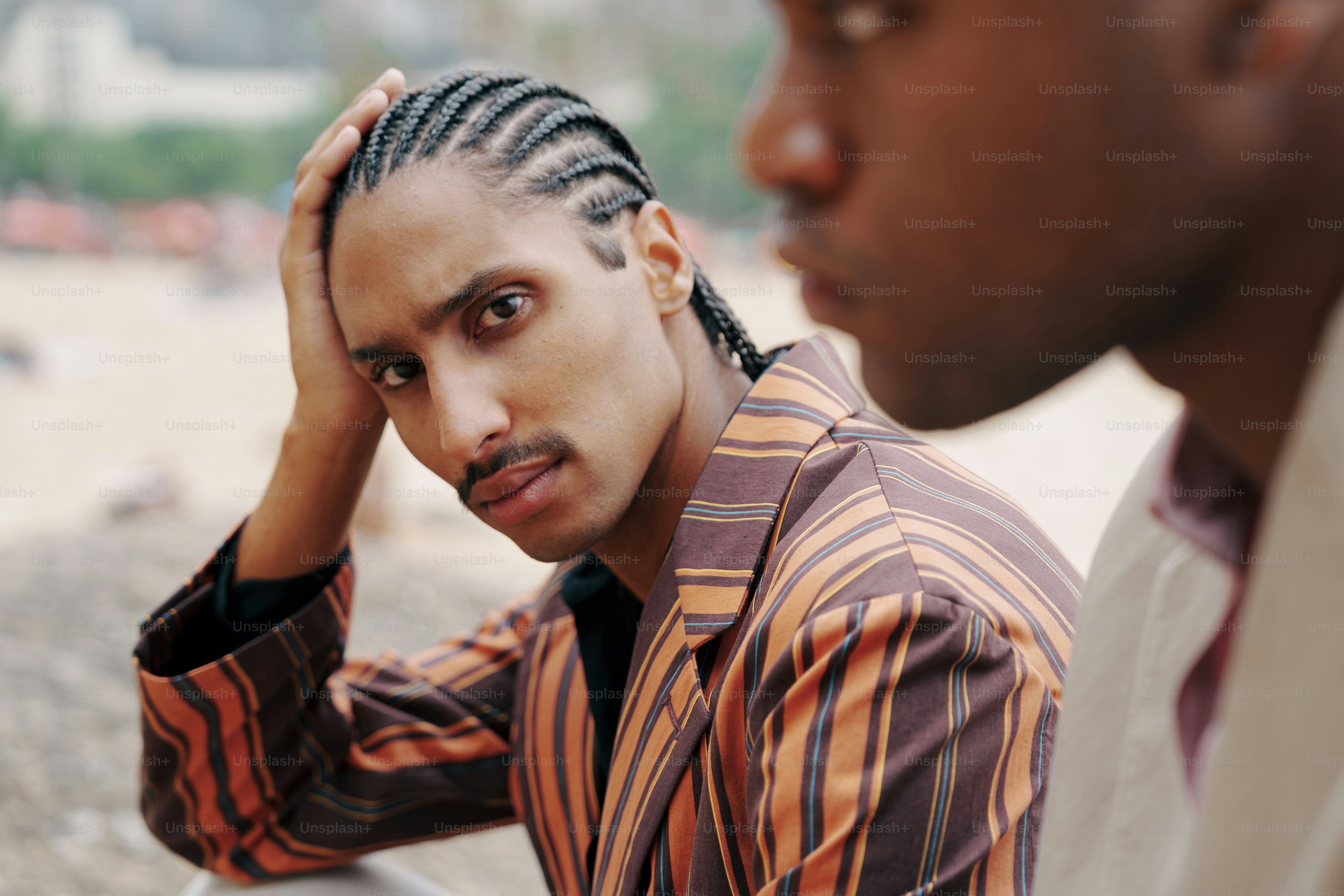 Man with braids and mustache wearing striped jacket