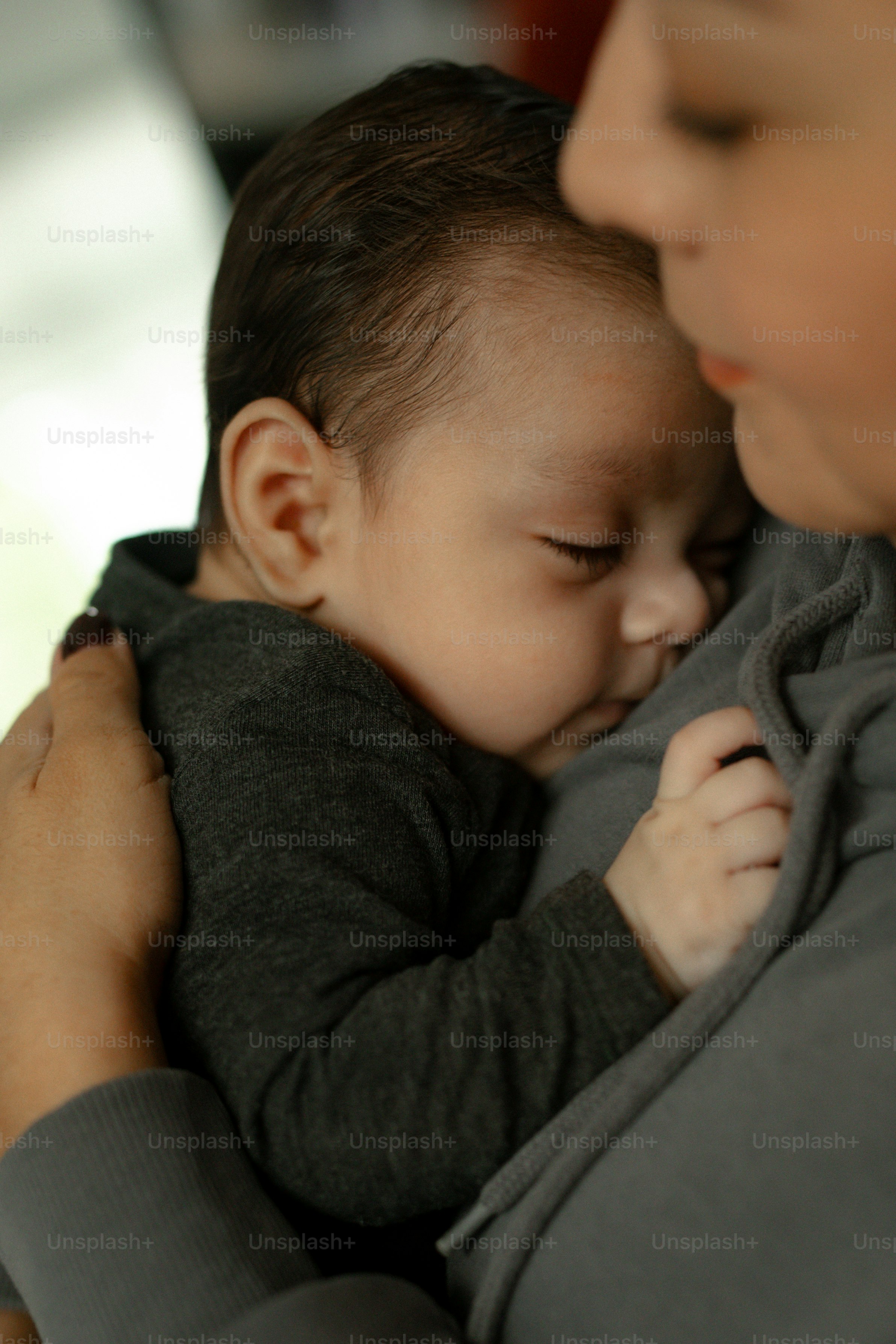 Mãe segurando seu bebê dormindo perto