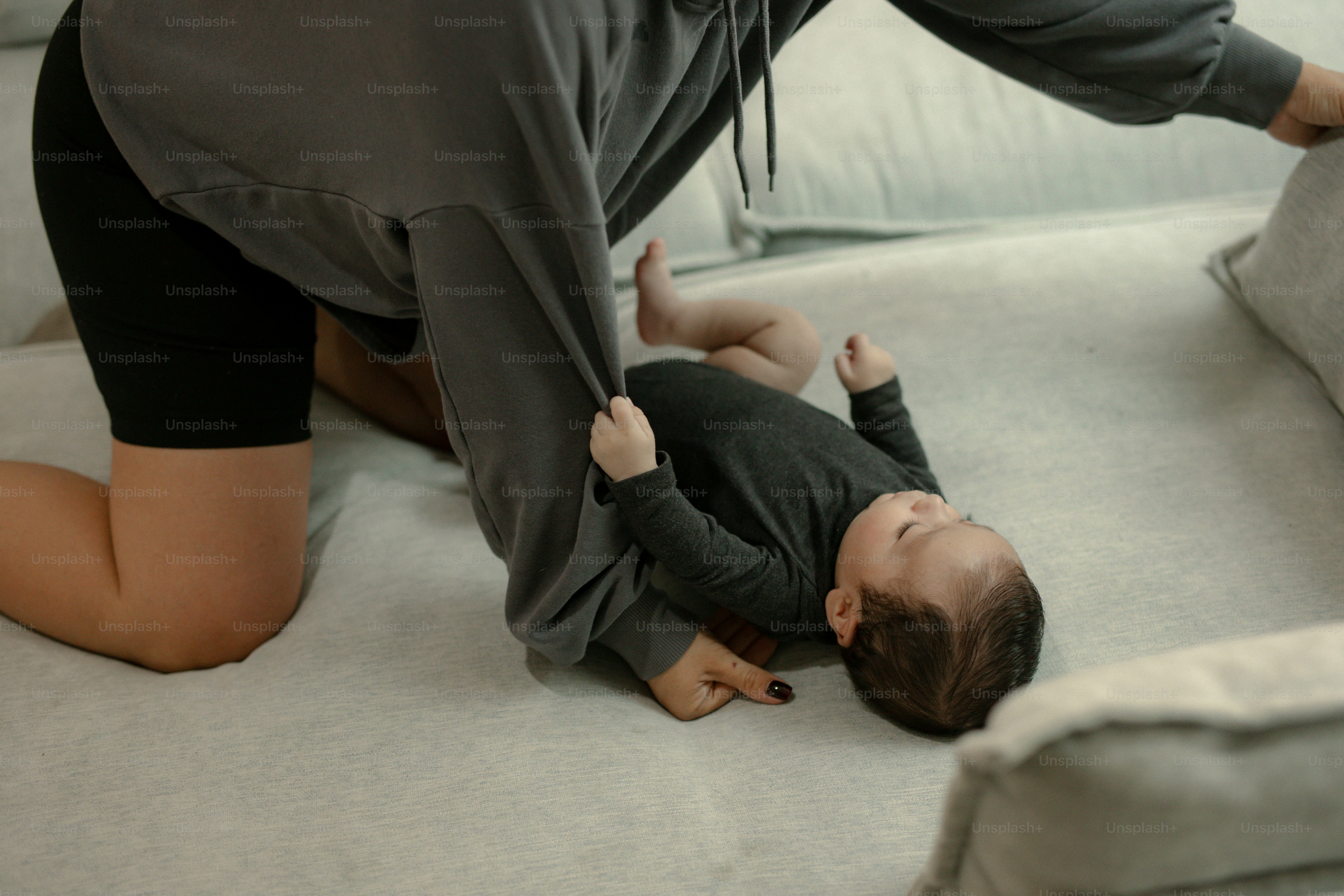 Adulto brincando com um bebê no sofá