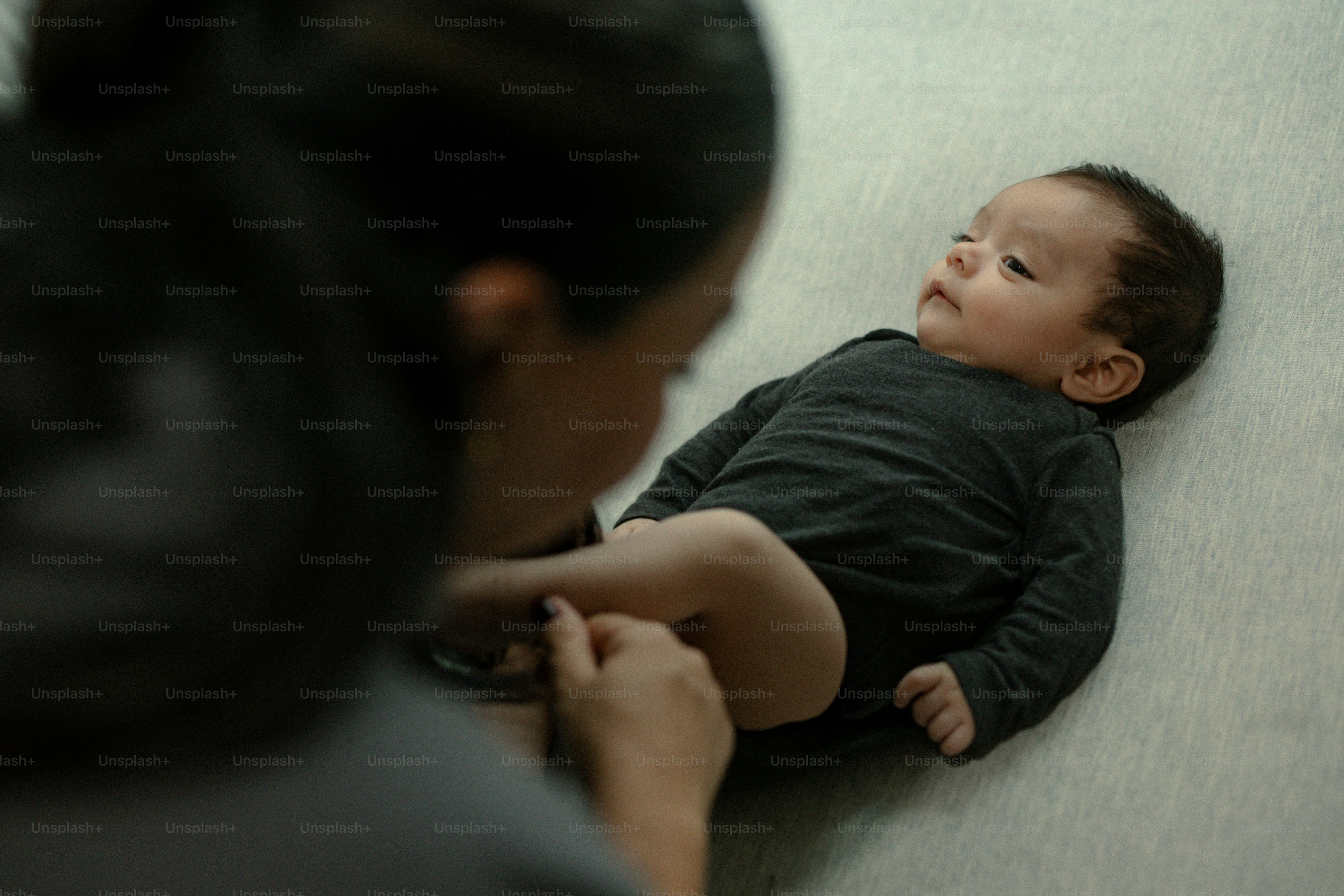 Mãe vestindo seu bebê com um macacão escuro.