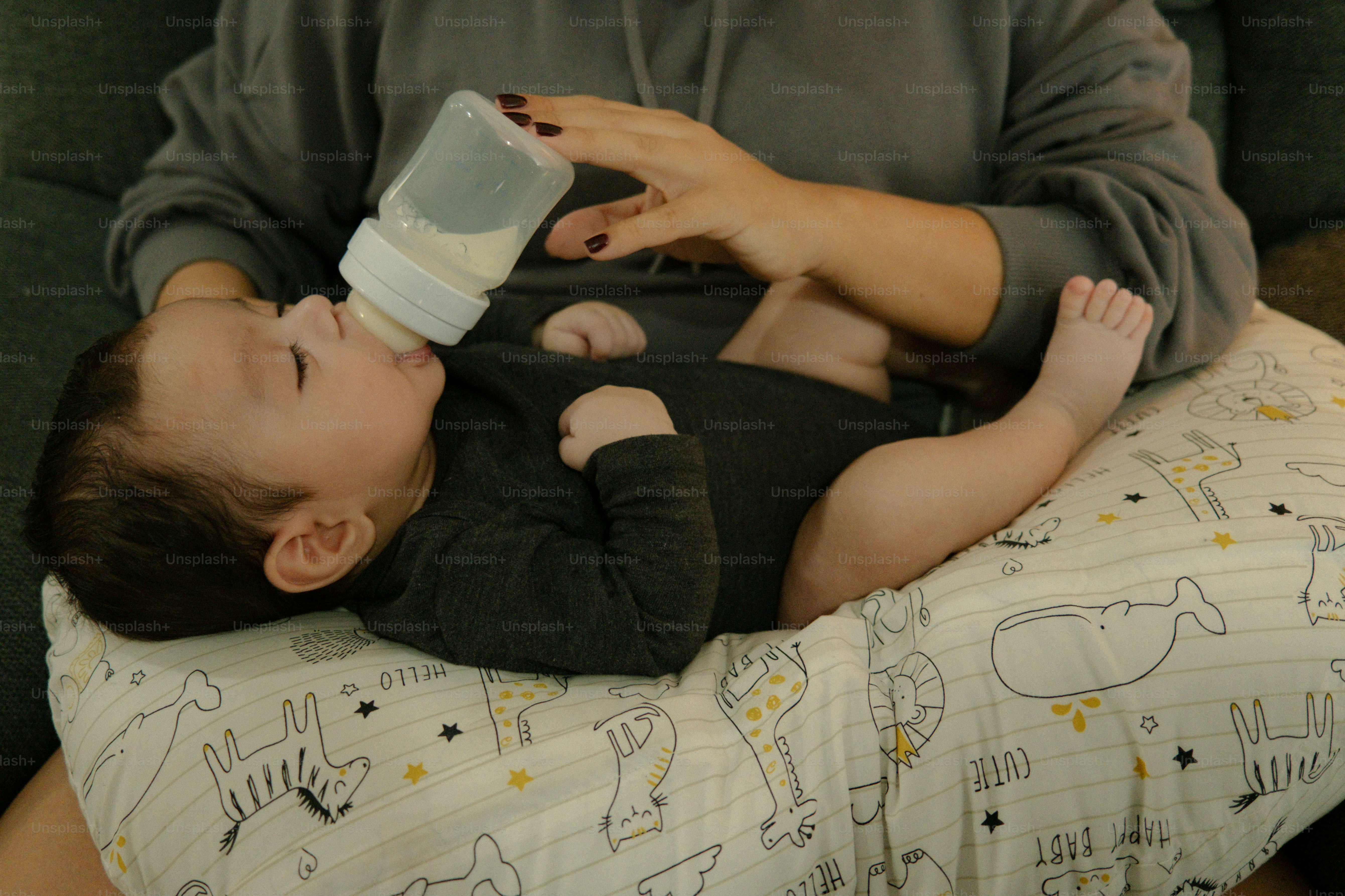 Mãe alimentando o bebê com mamadeira em um travesseiro