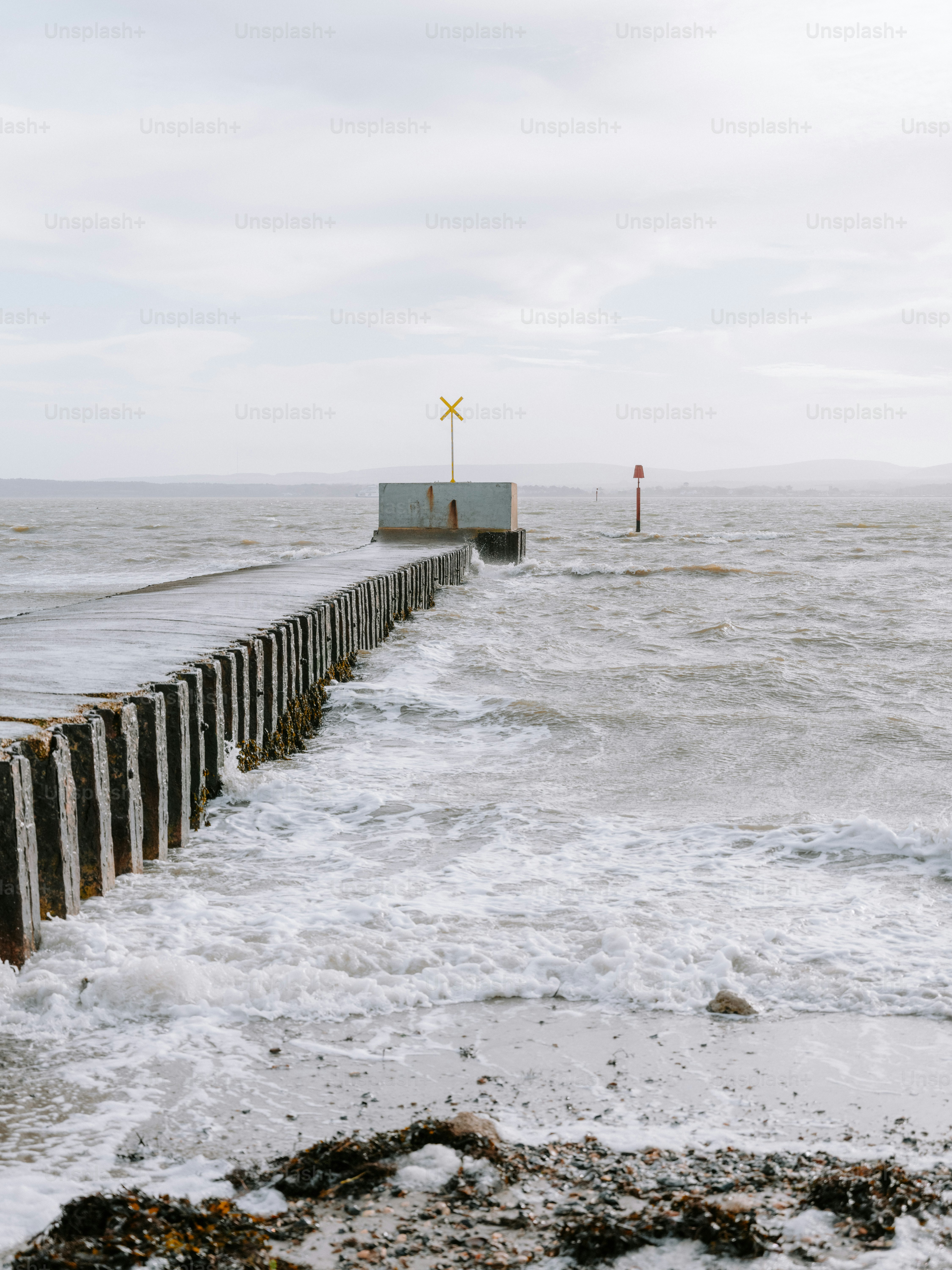 Waves crash against a pier on a cloudy day