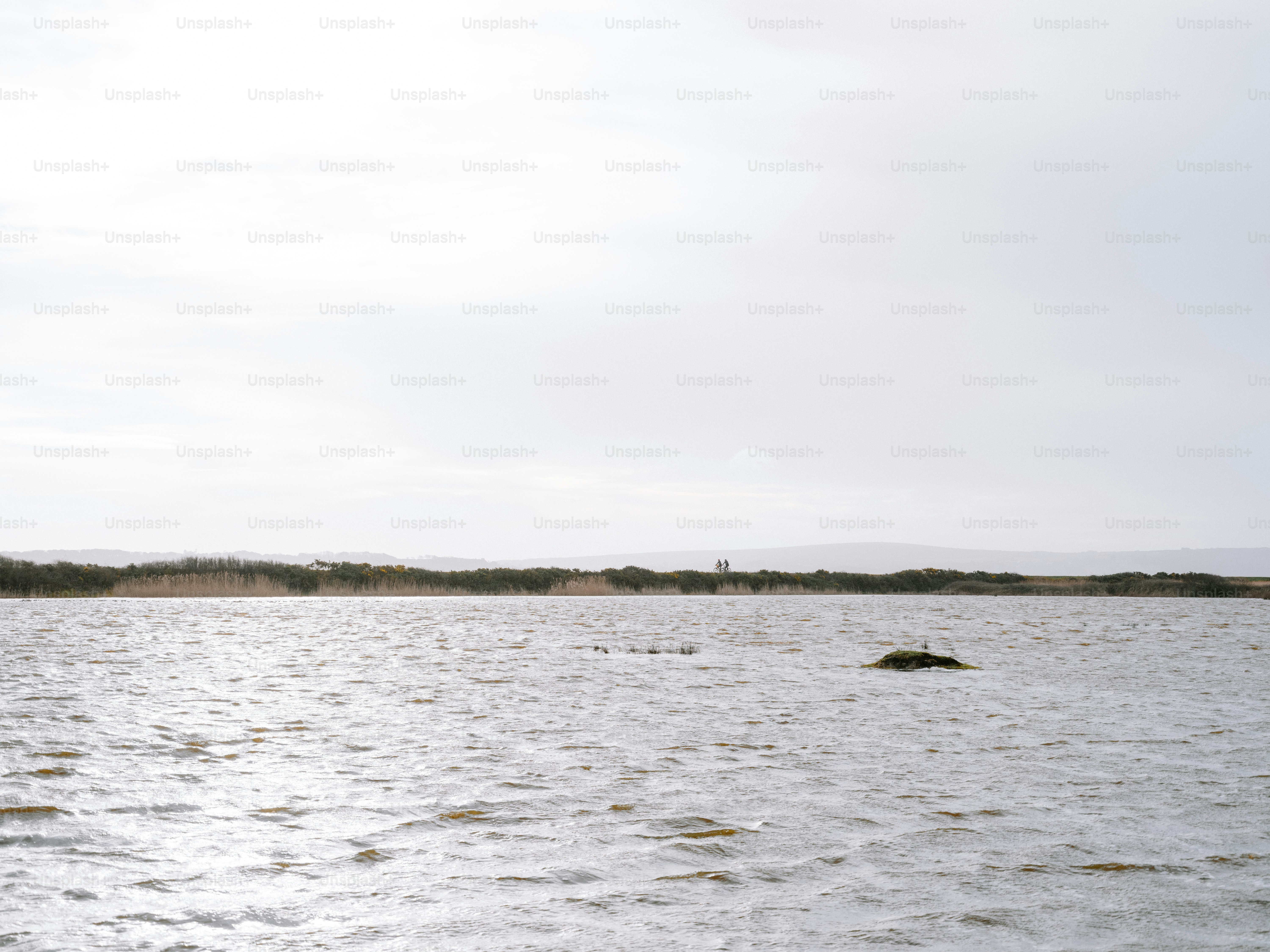 Eau calme avec un rivage lointain sous un ciel nuageux