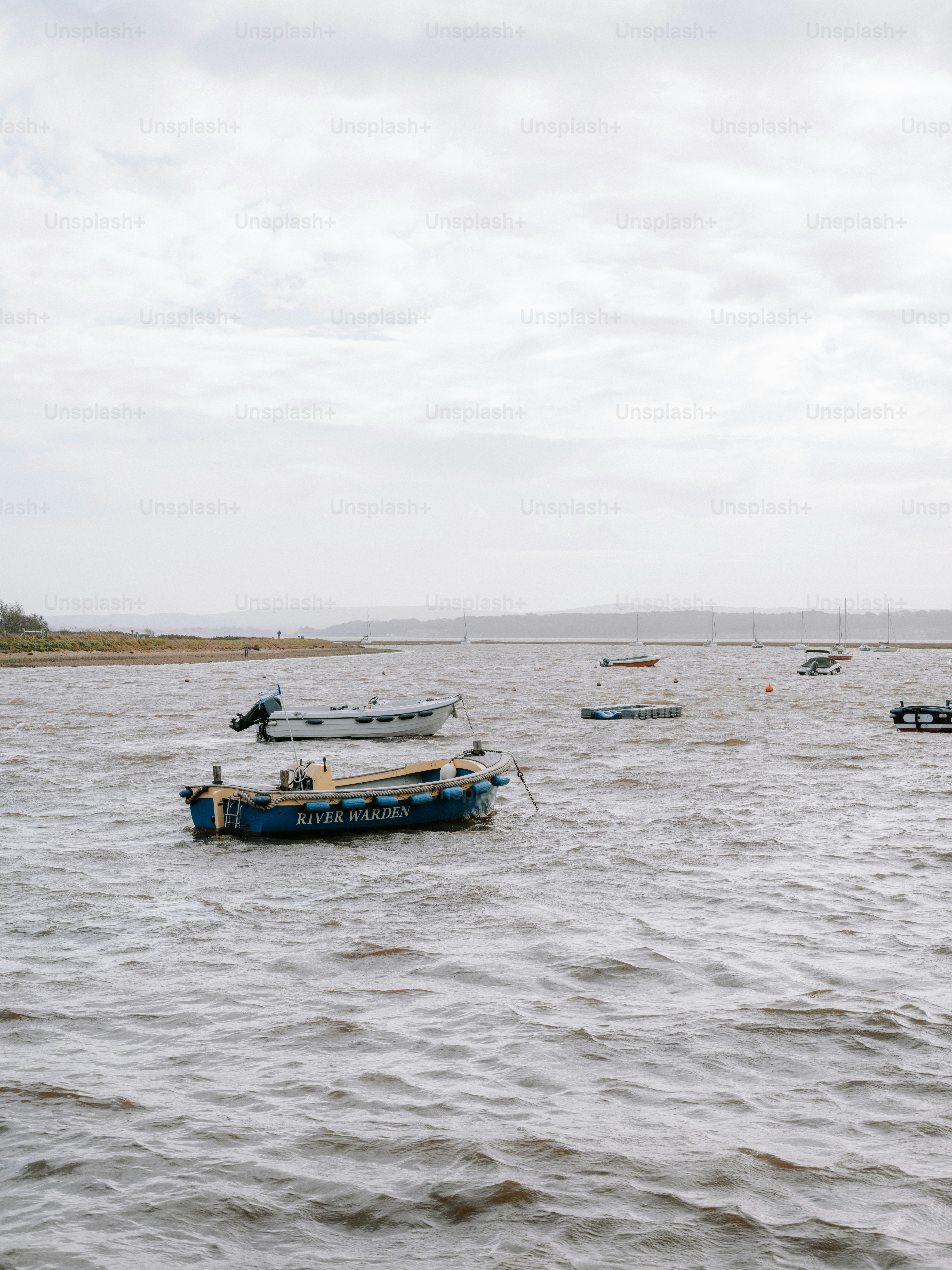 Several small boats float on choppy water