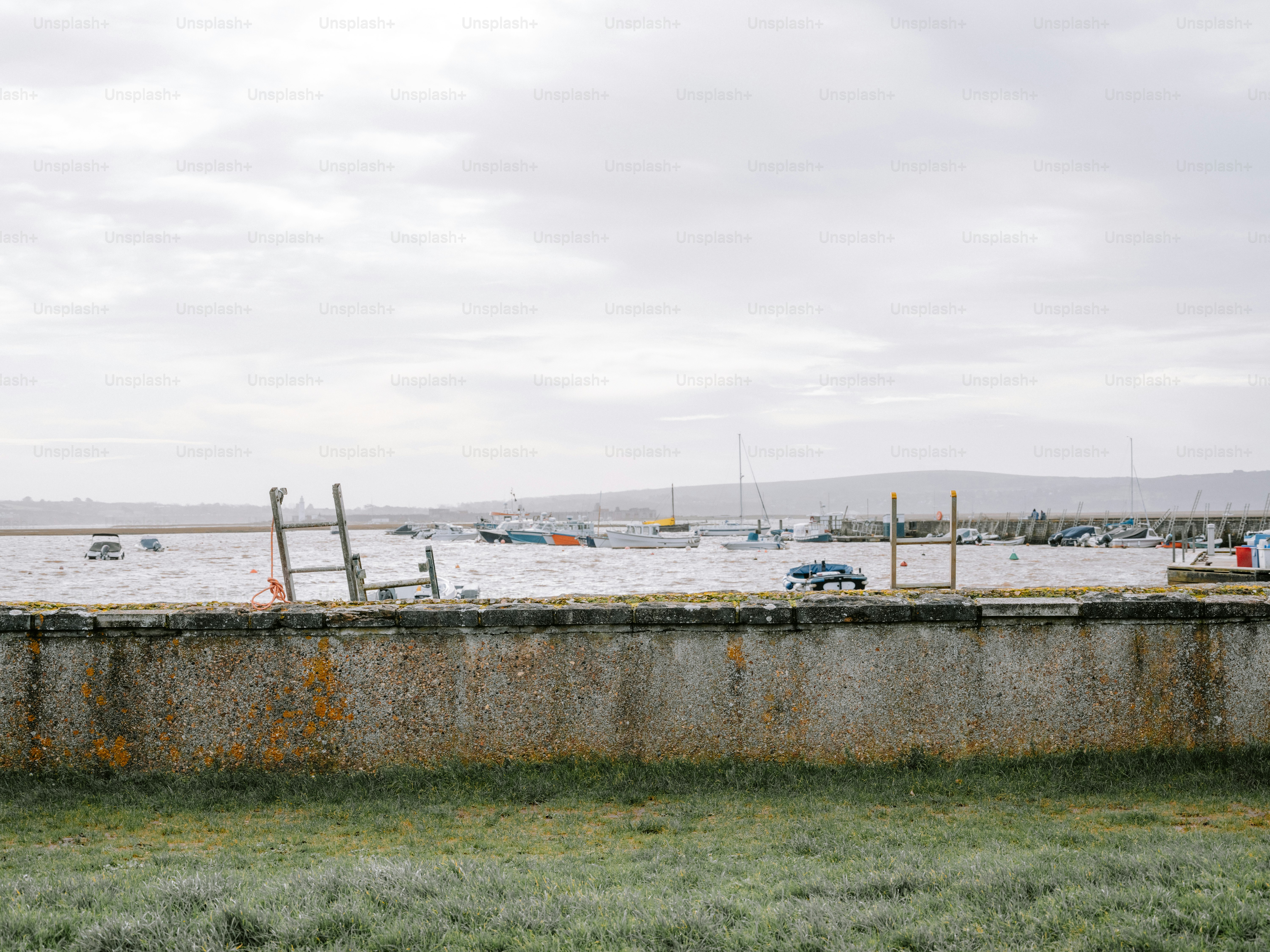 Boats docked in a harbor with a stone wall foreground