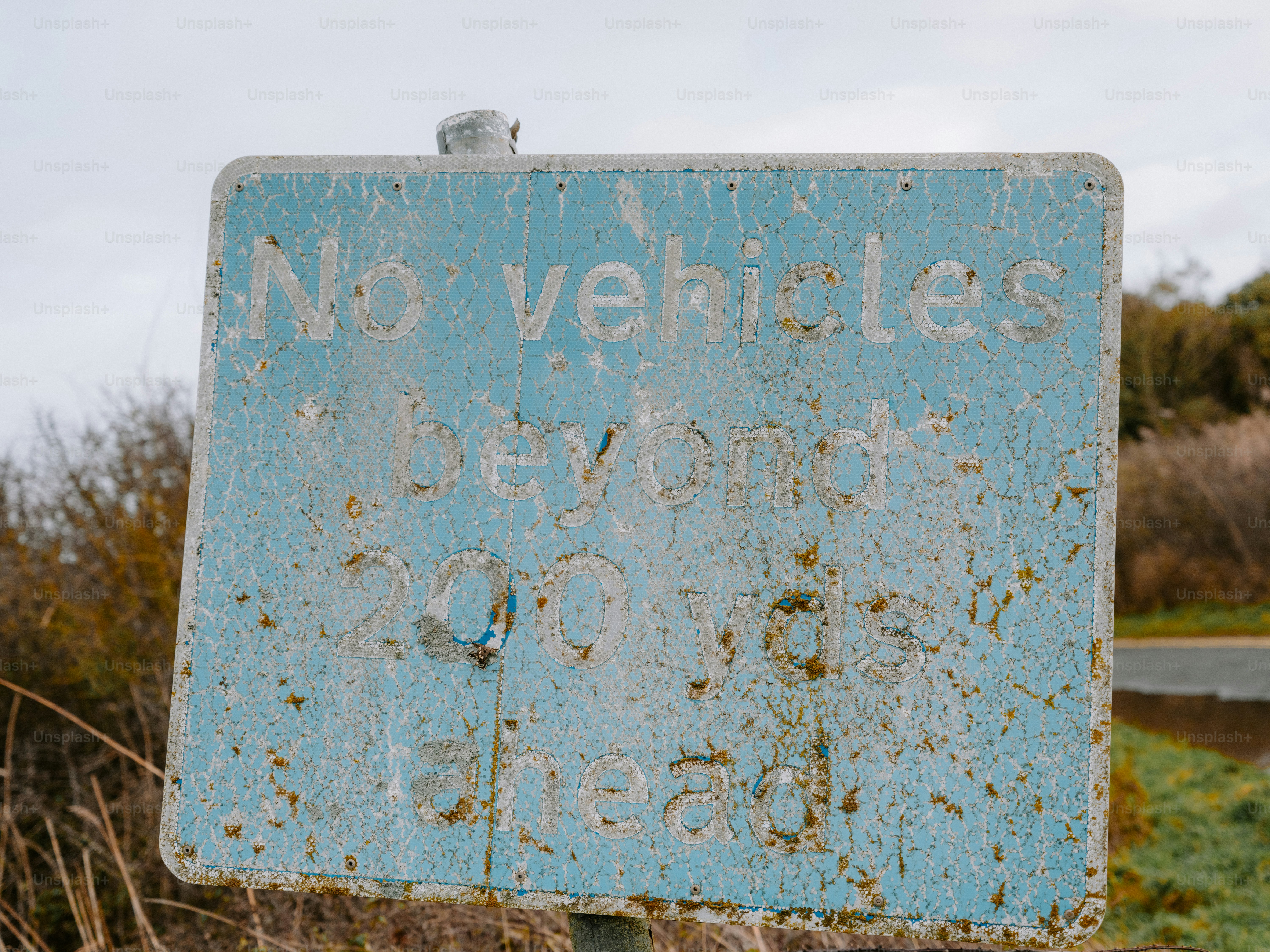 Weathered blue sign reads 'no vehicles beyond 200 yards ahead'.