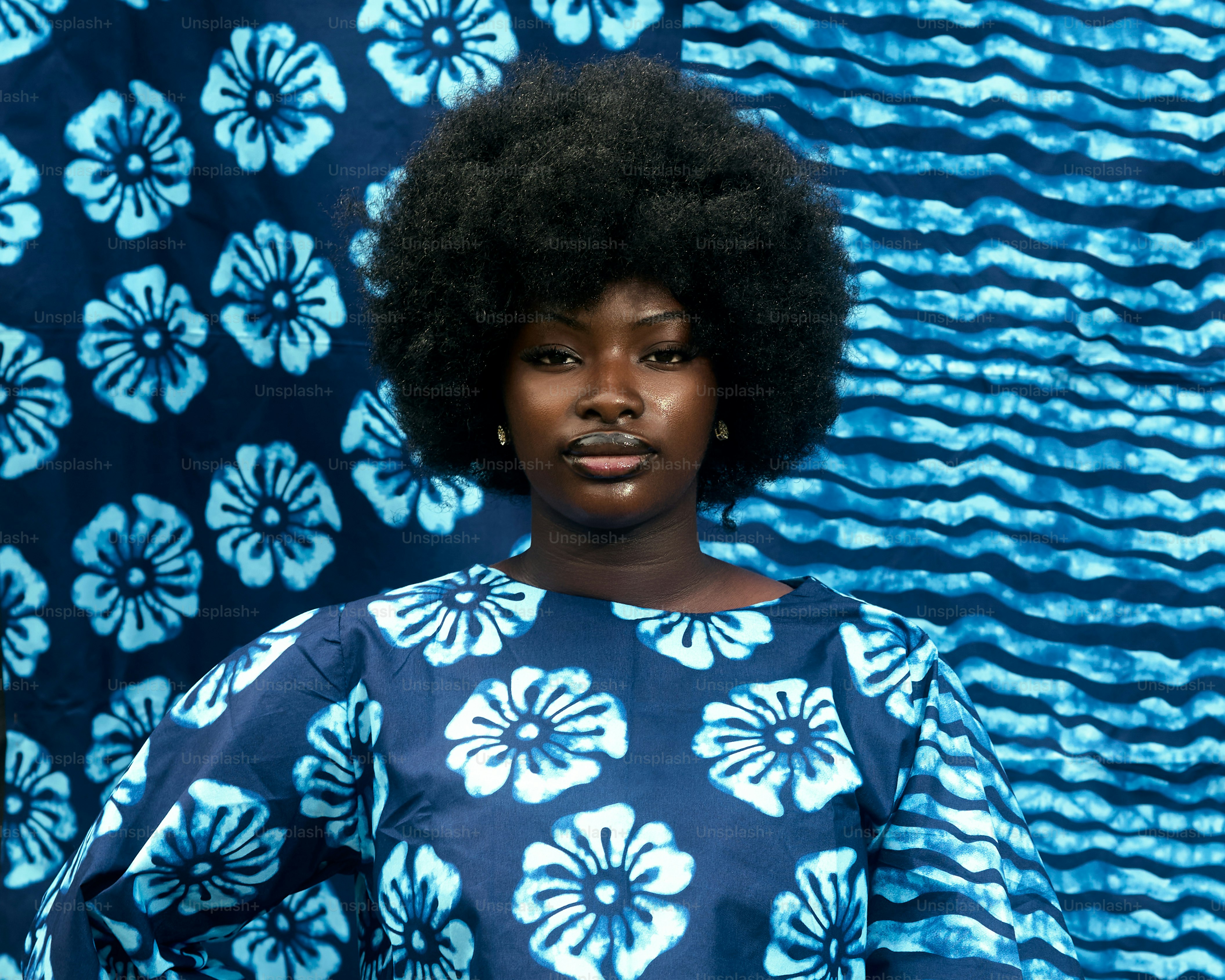 Junge Frau mit Afro in blauem Kleid mit Blumenmuster.