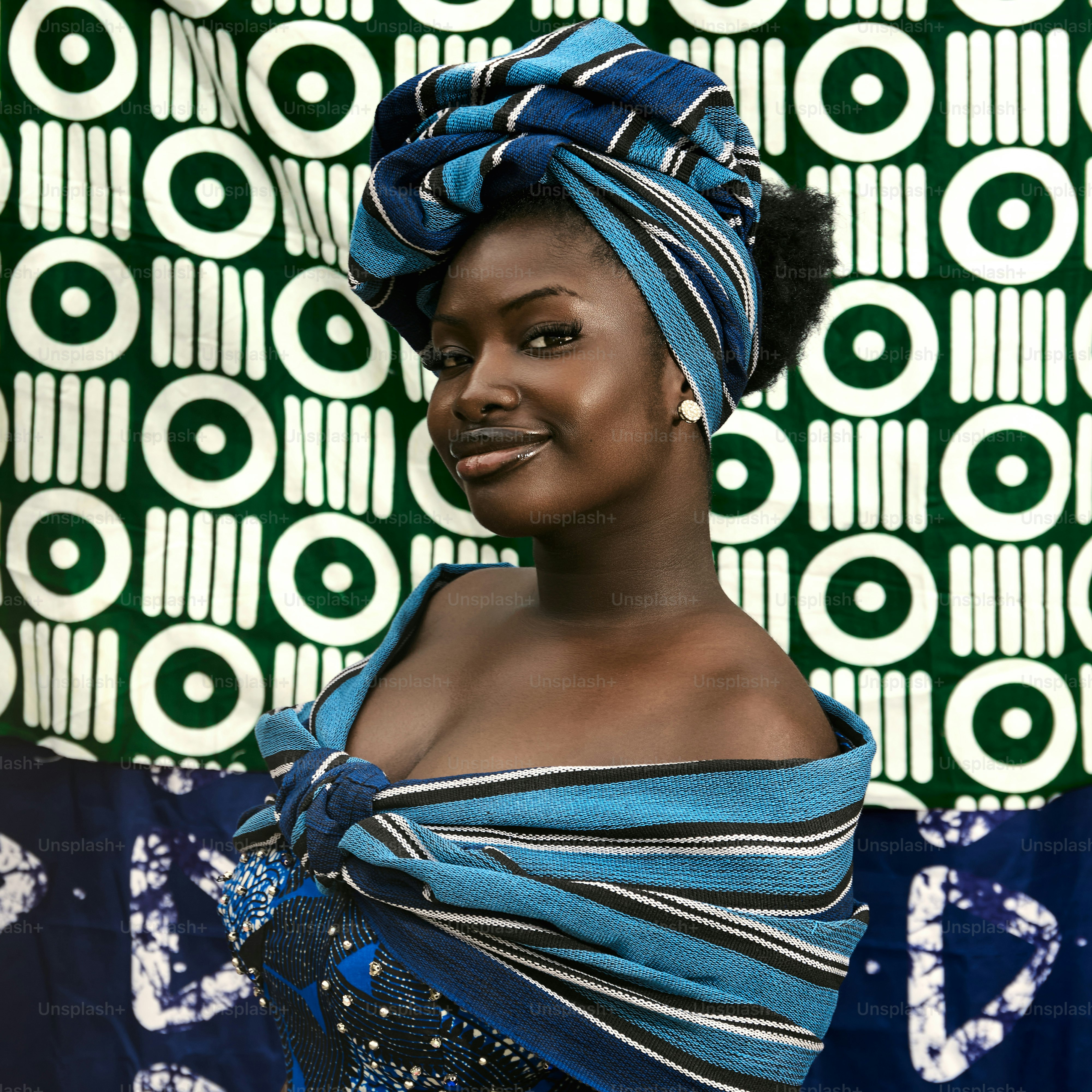 A woman in a blue headwrap and traditional clothing.