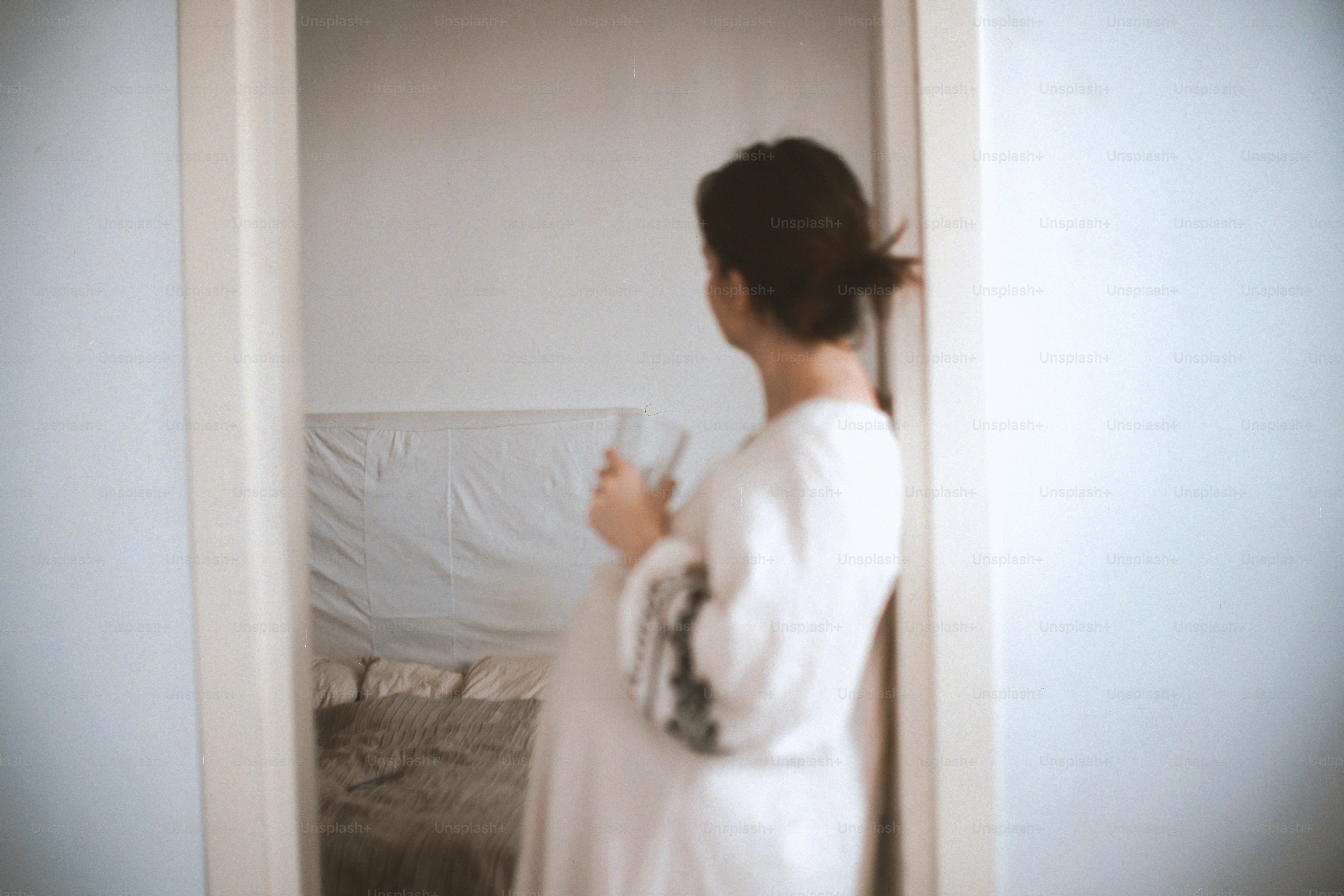 Femme en robe blanche tenant du verre, se regardant dans un miroir