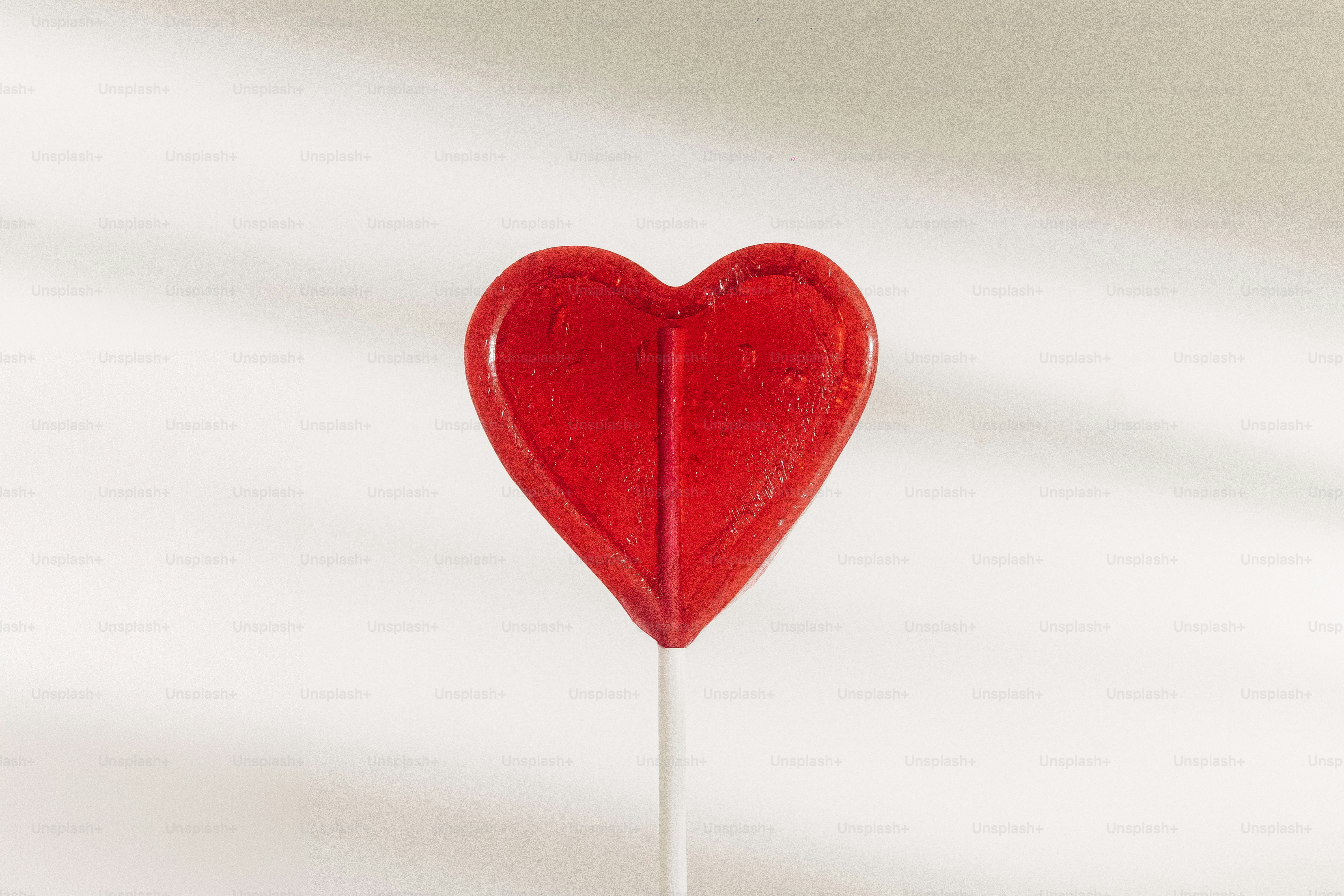 A single red heart-shaped lollipop on a white background.