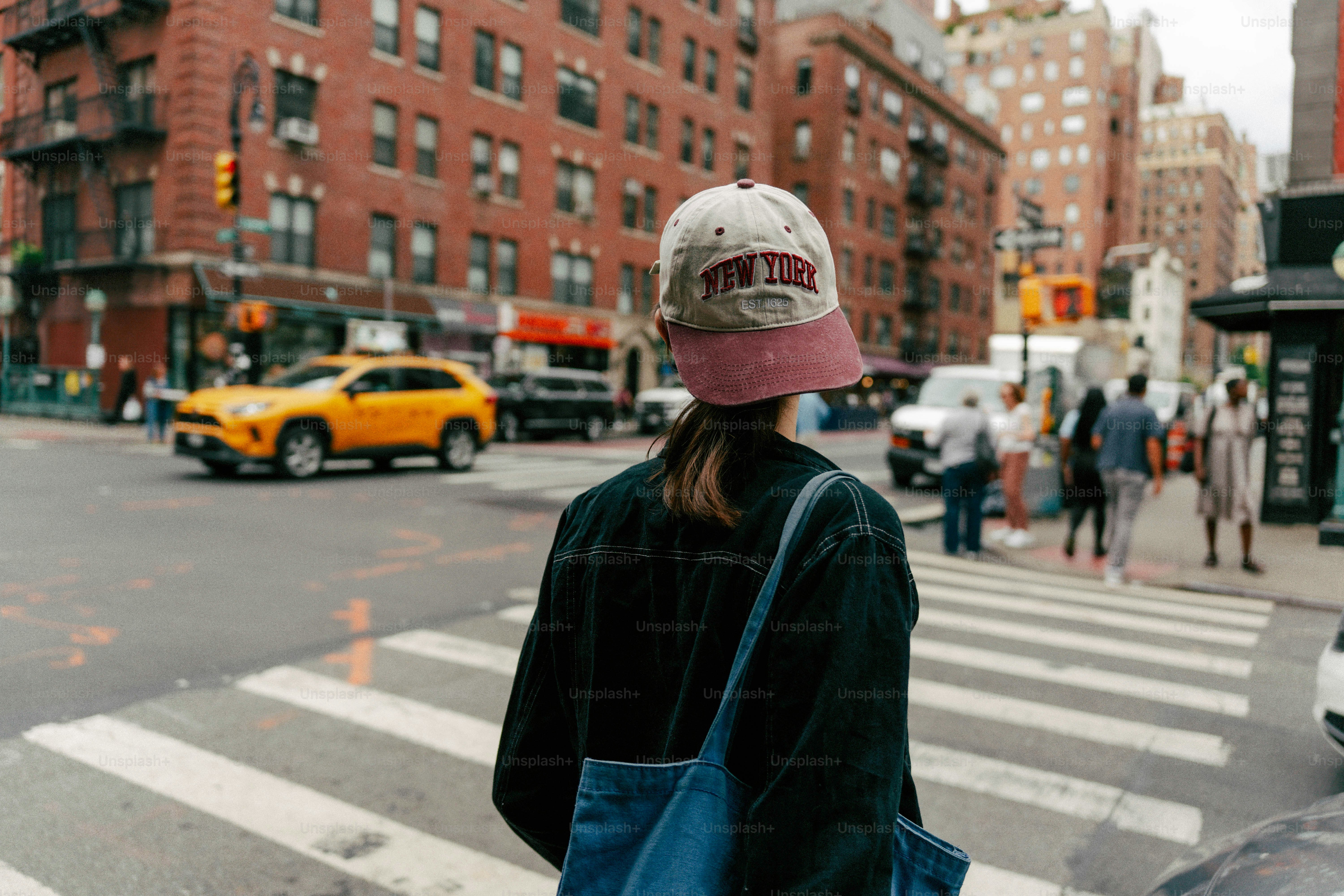 뉴욕 모자를 쓴 여성이 분주한 거리를 건너고 있다.