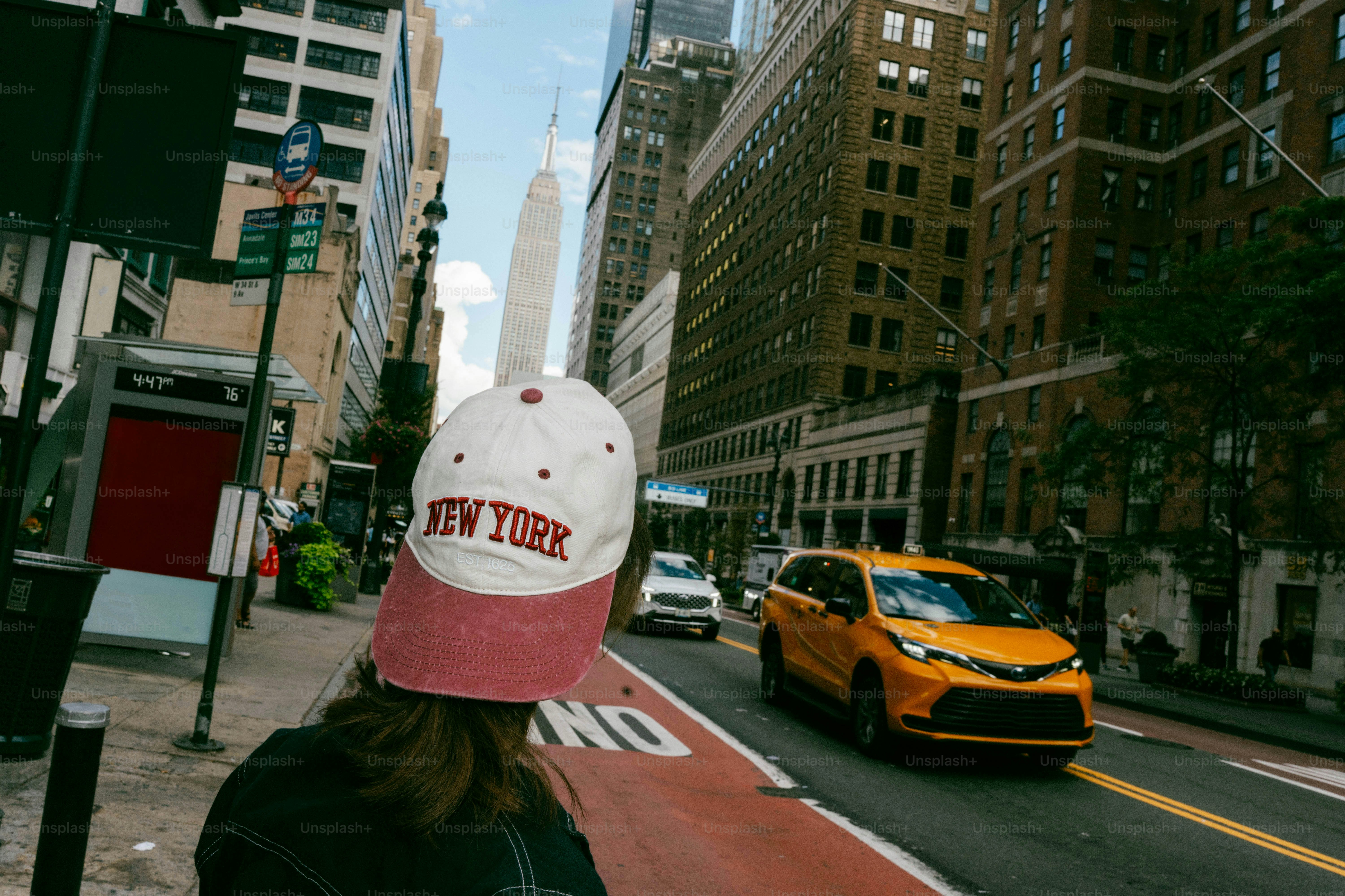 뉴욕 모자를 쓴 사람이 시티 스트리트에 서 있다