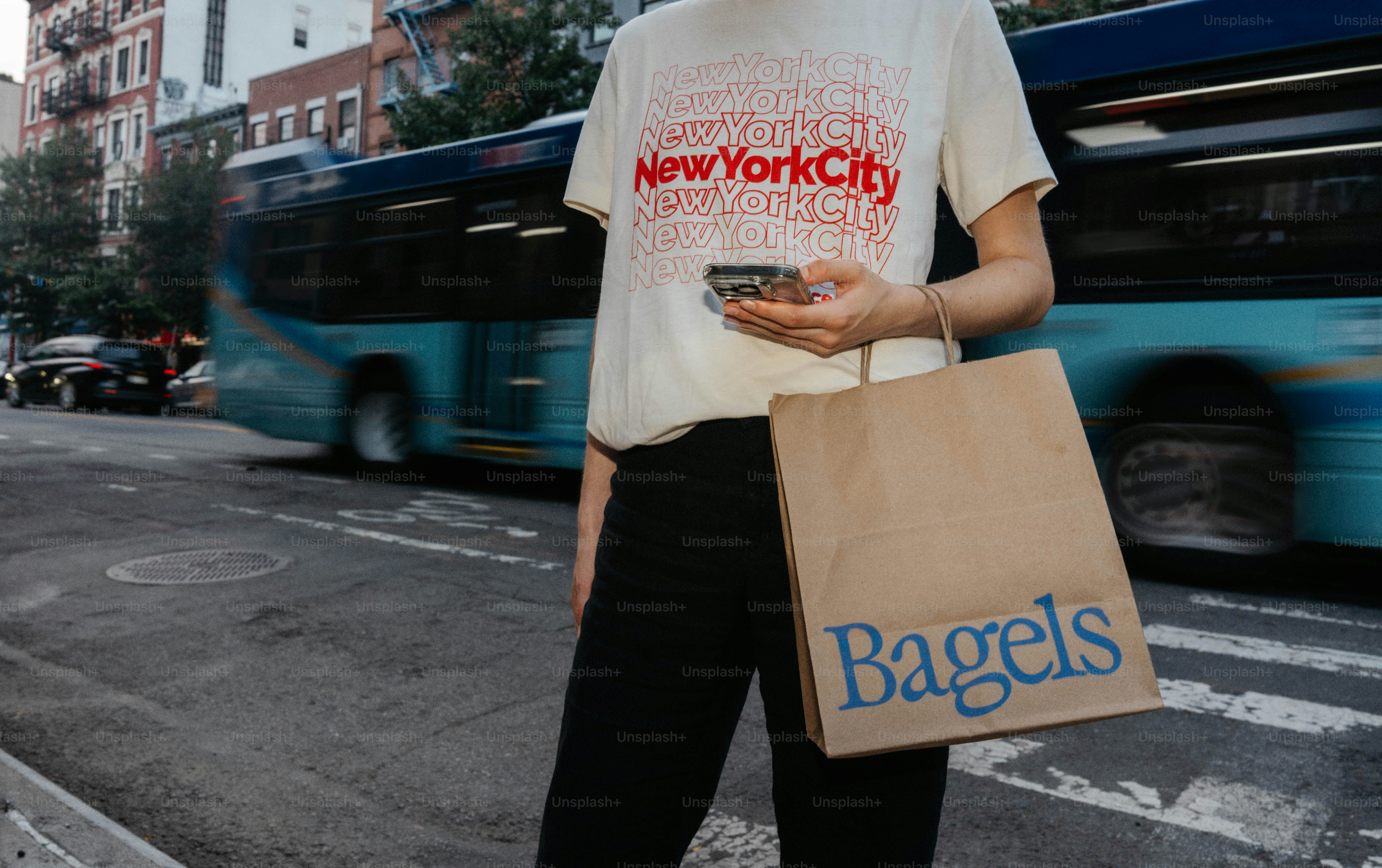 Persona con una bolsa de bagels en la calle con autobús