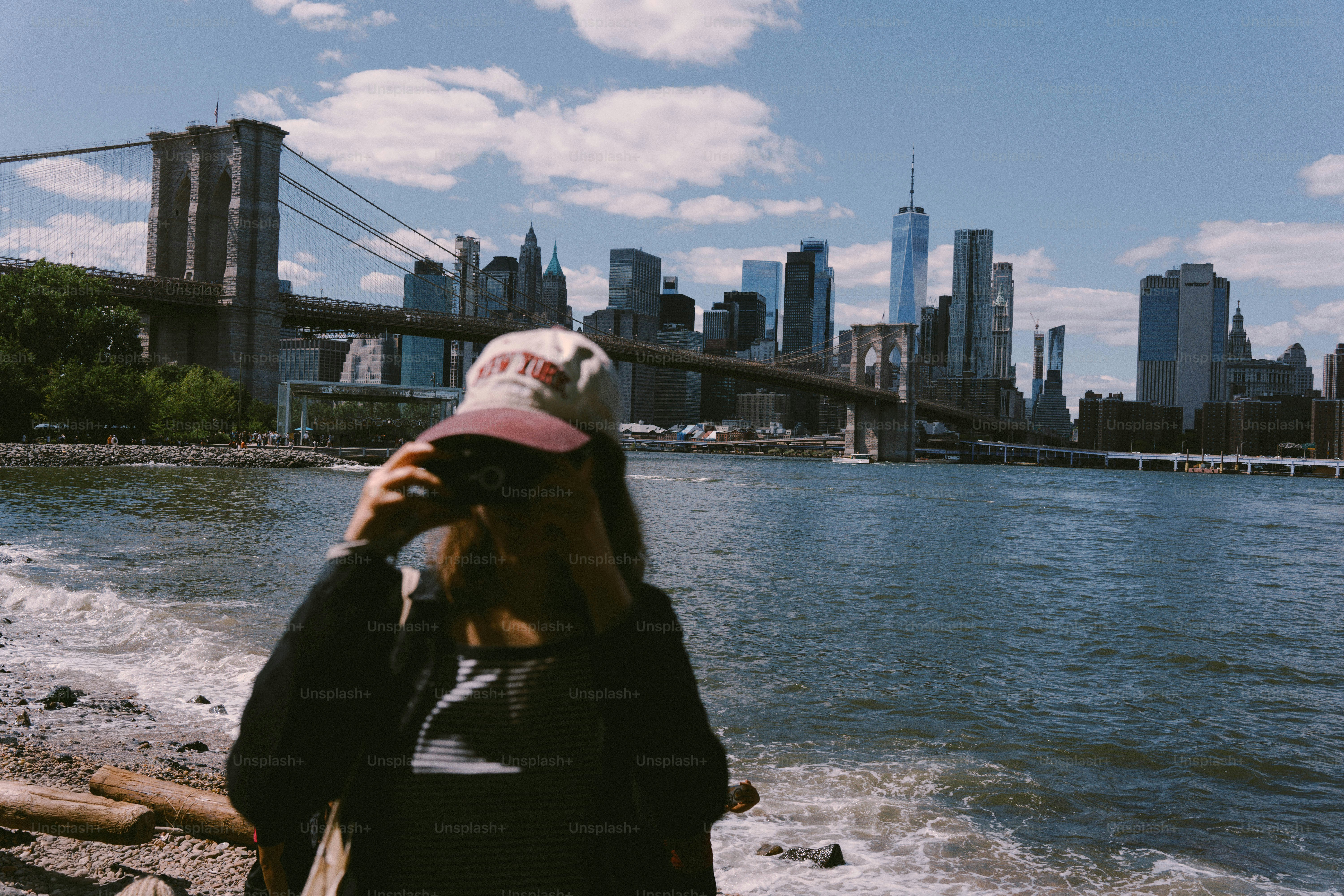 브루클린 브리지 옆의 모자 쓴 여성, 도시 스카이라인이 배경입니다