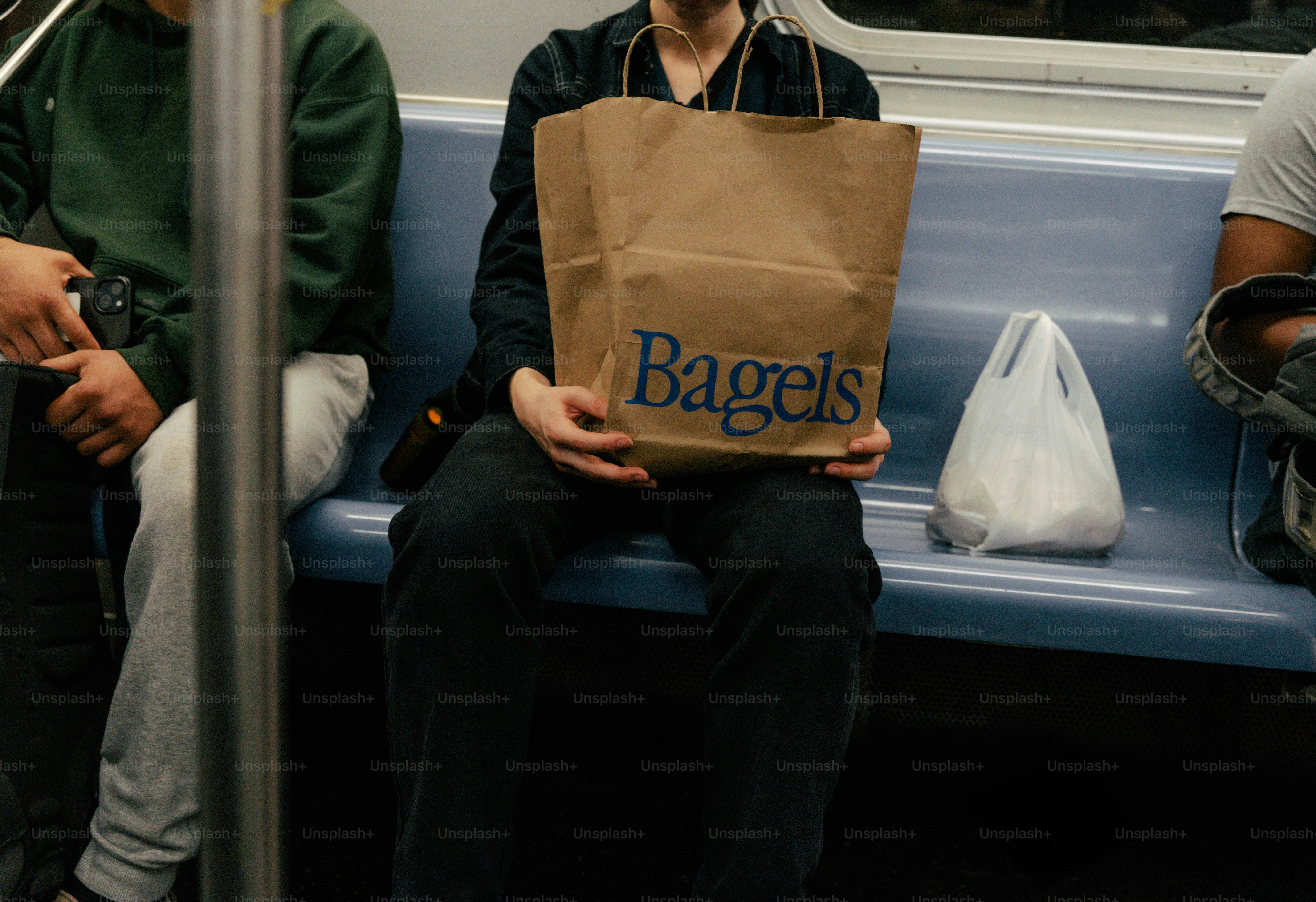 La persona sostiene una bolsa de papel con "bagels" escrito en ella.