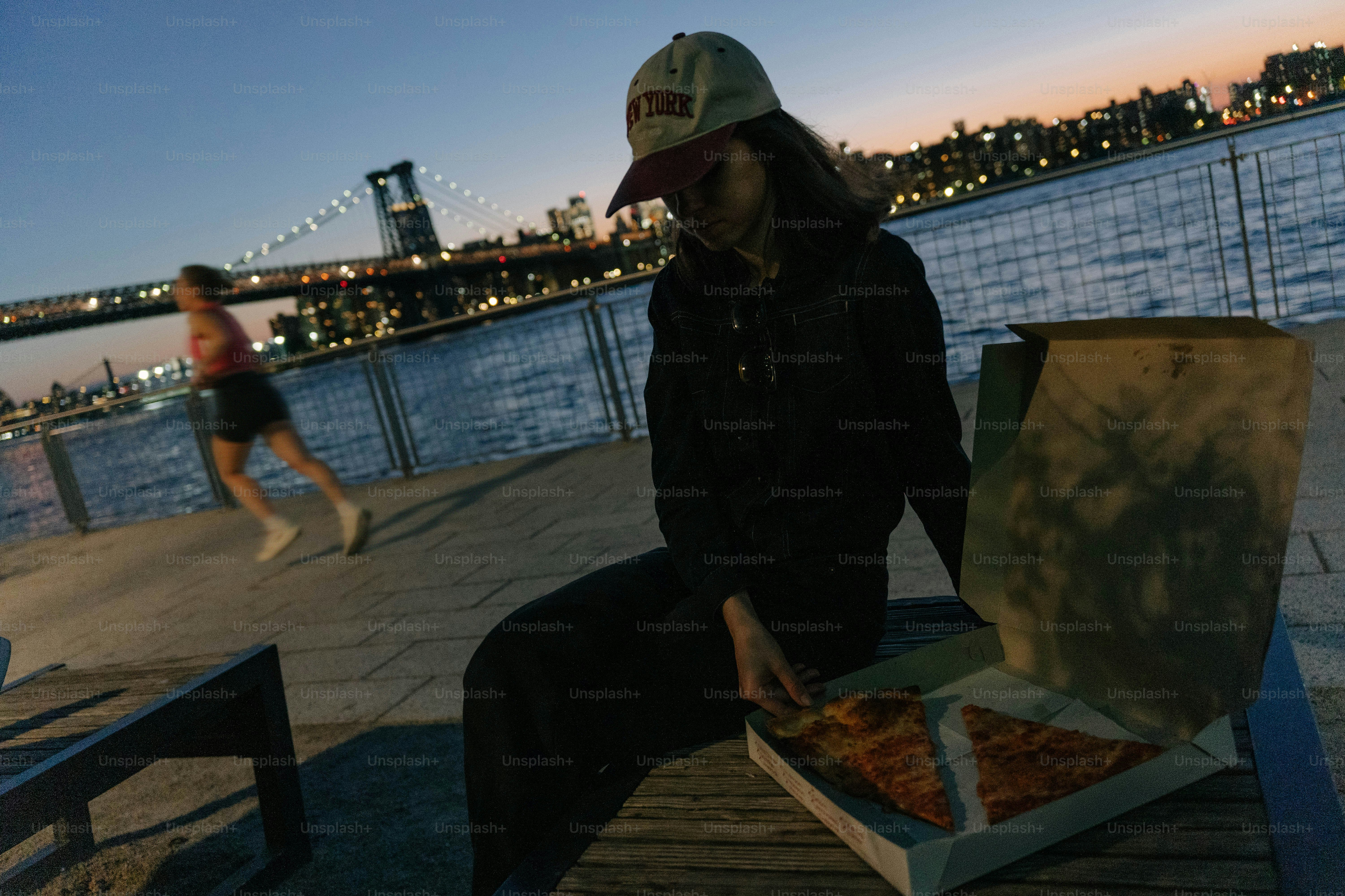 해질 무렵 물가에서 피자를 먹는 여성