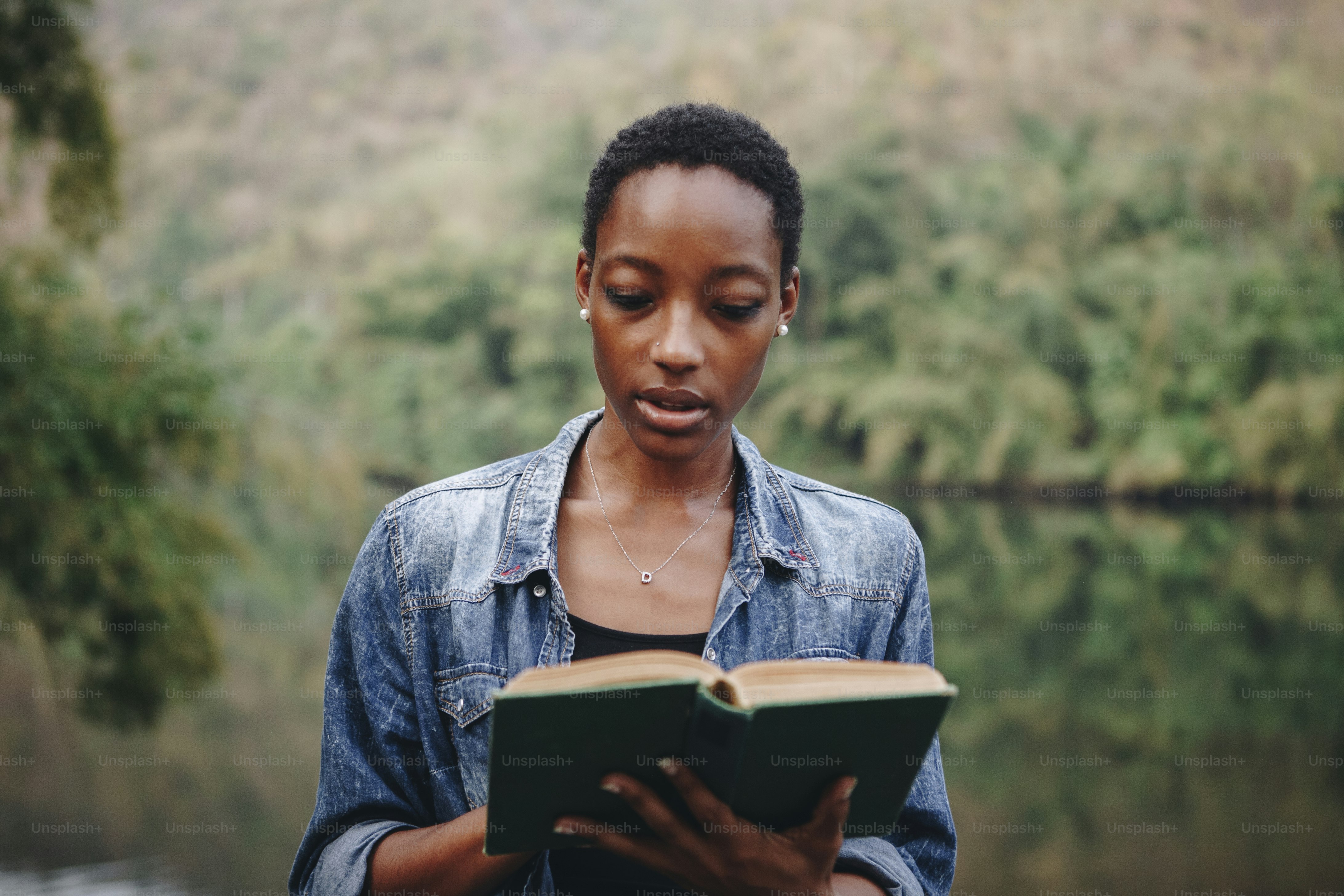 African American woman alone in nature reading a book leisure concept