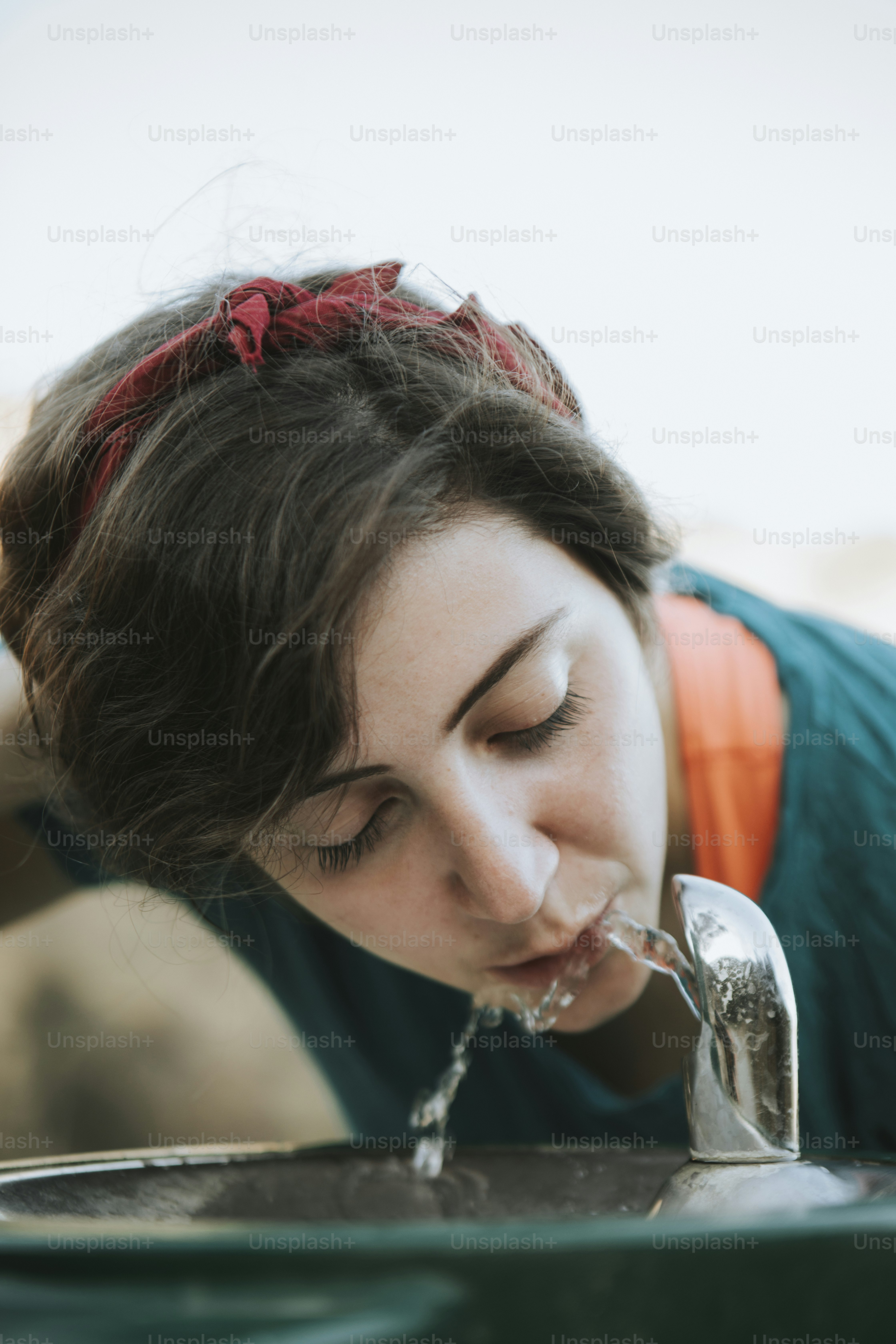 Mulher bebendo água de uma fonte de água