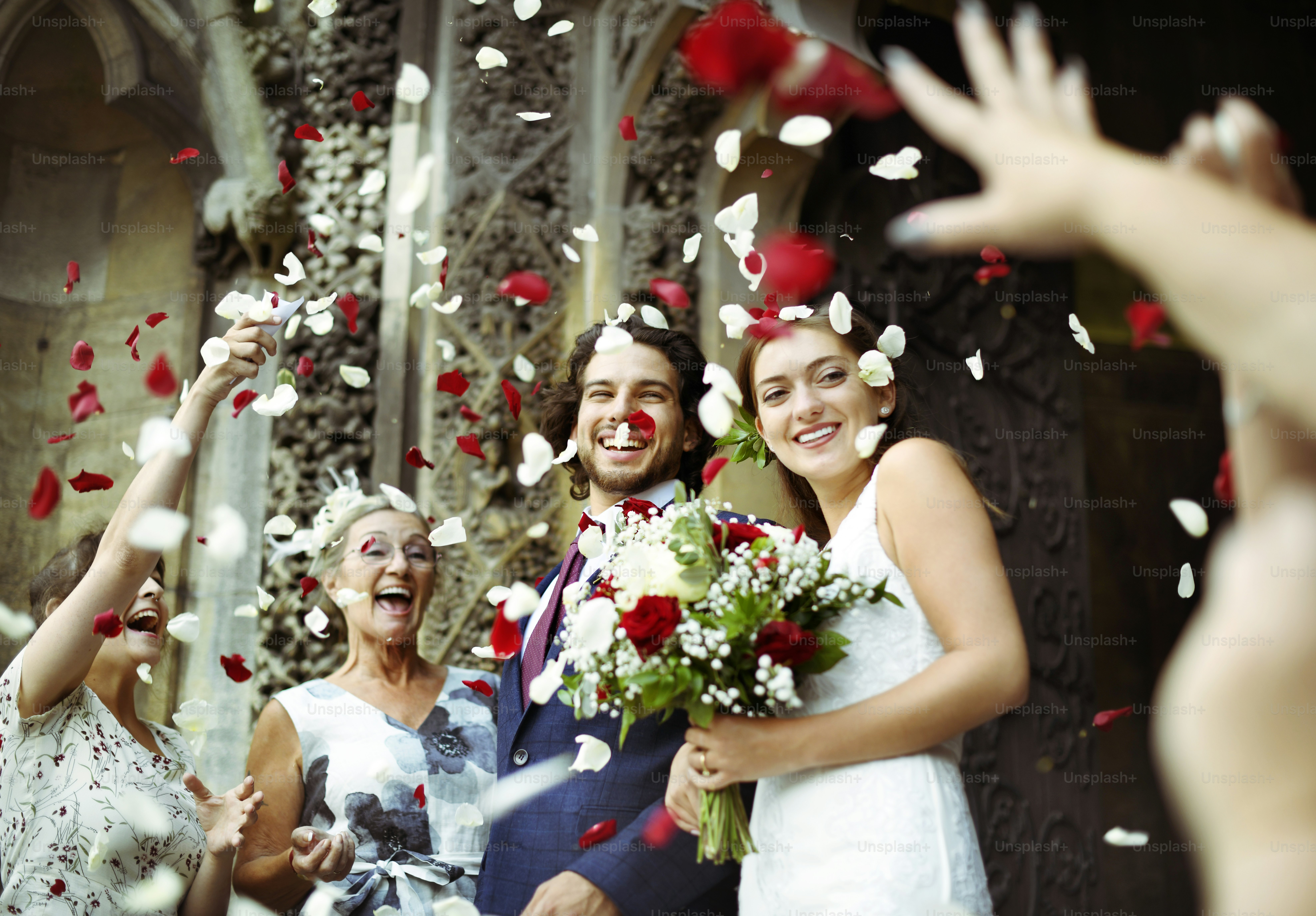 Family throwing rose petals at the newly wed bride and groom photo ...