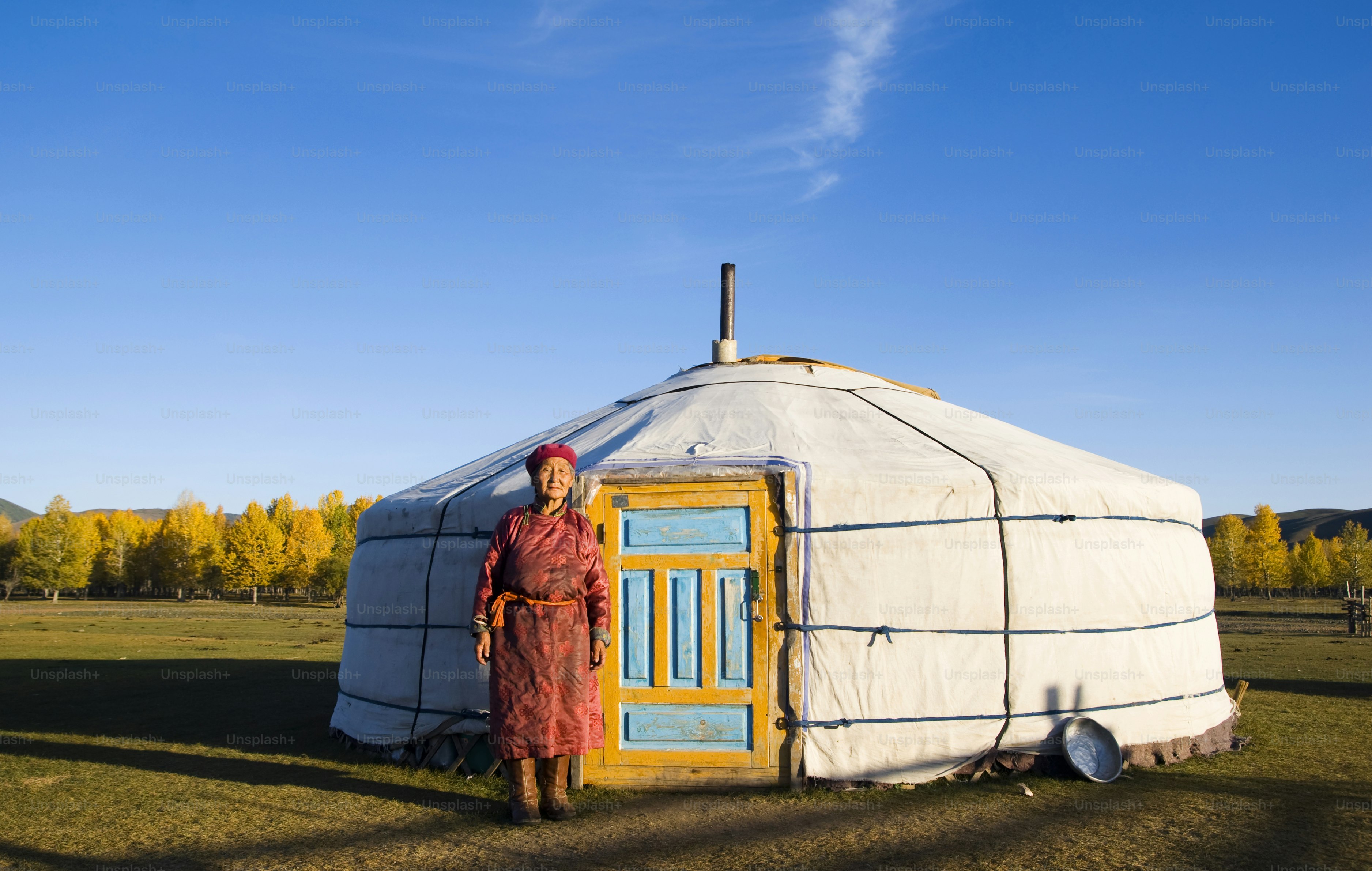 Woman in traditional clothing stands by a yurt