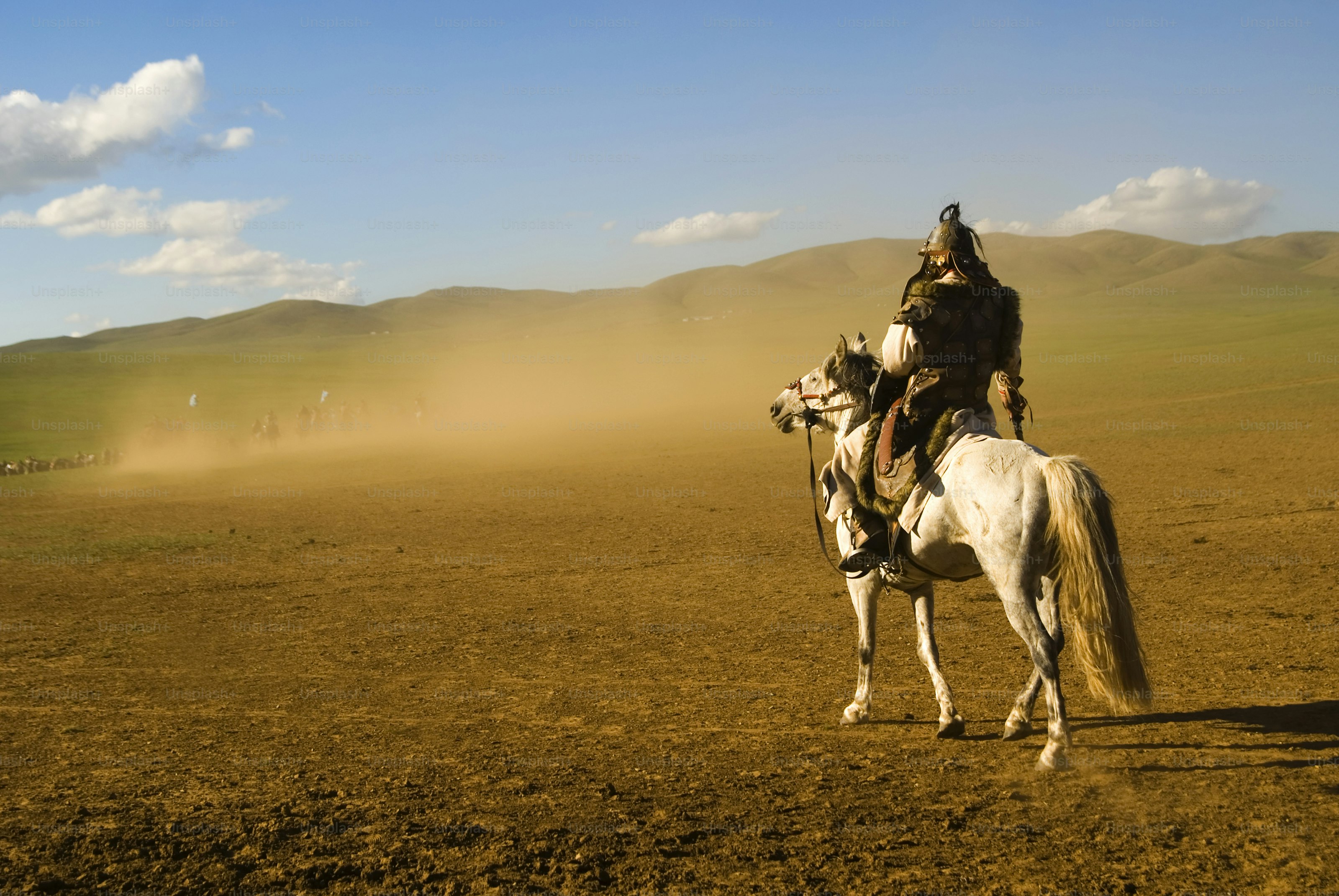 Warrior on horseback in a dusty, arid landscape.
