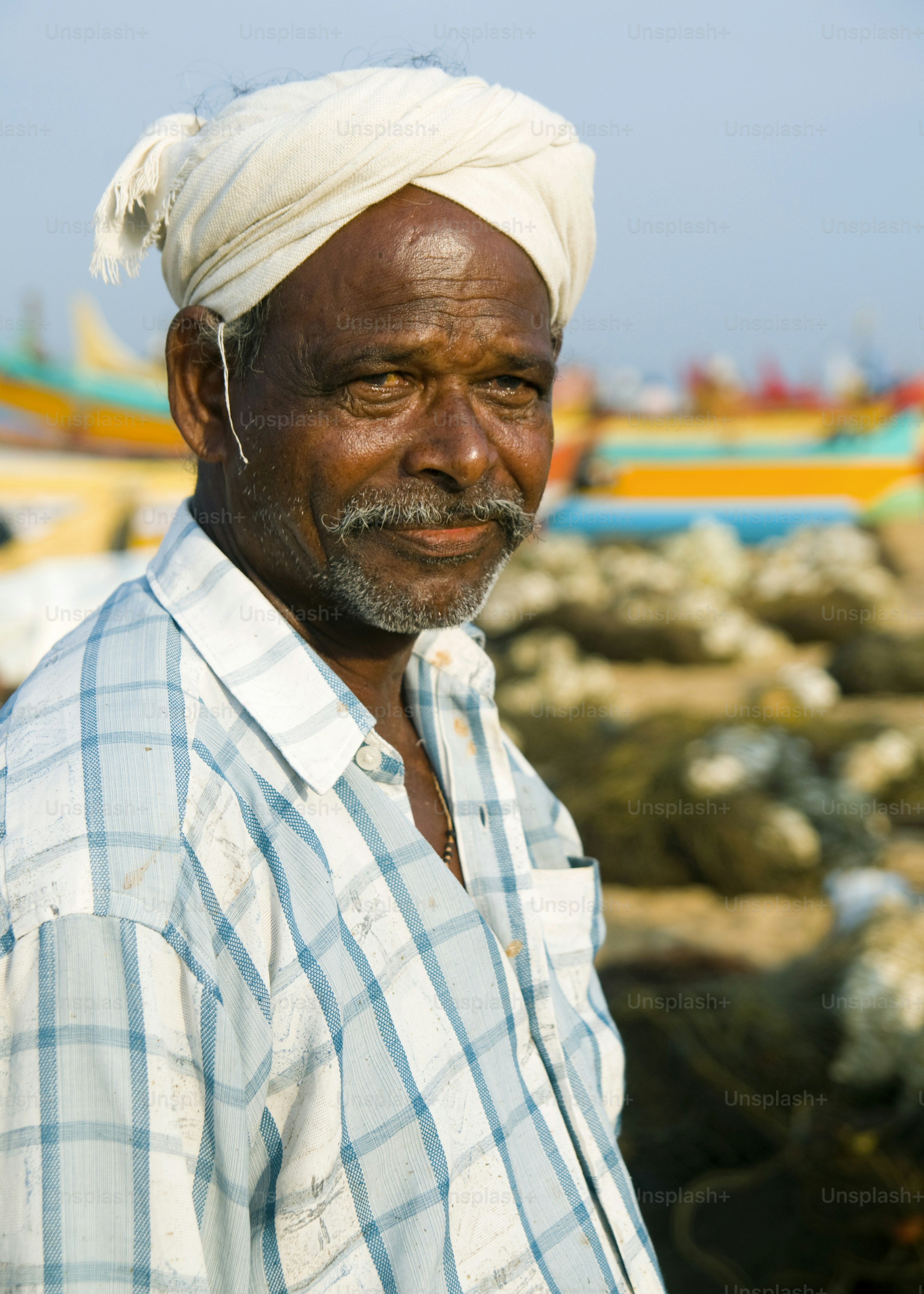 An elderly indian fisherman with a turban and mustache.