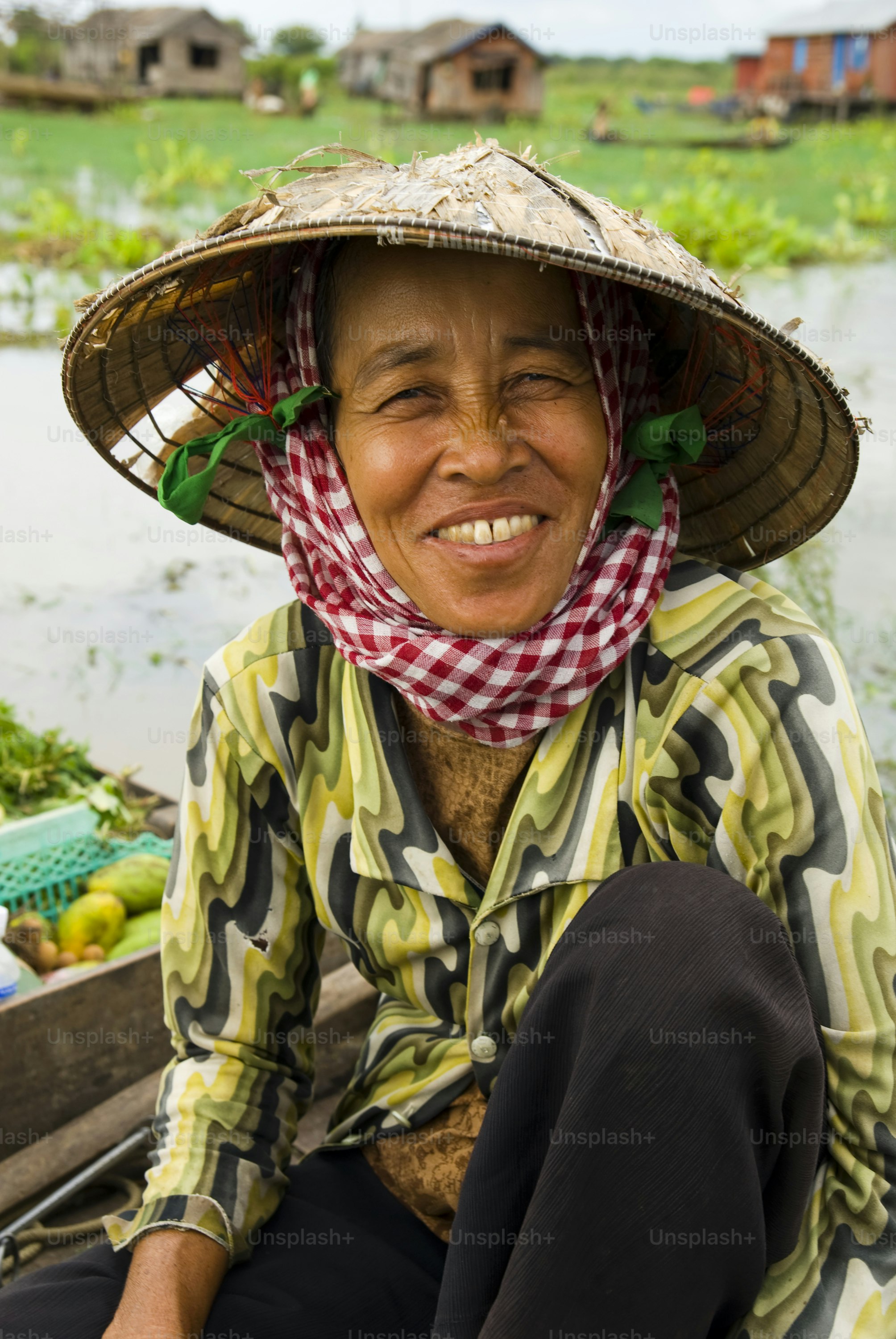 A smiling woman wearing a conical hat on a boat