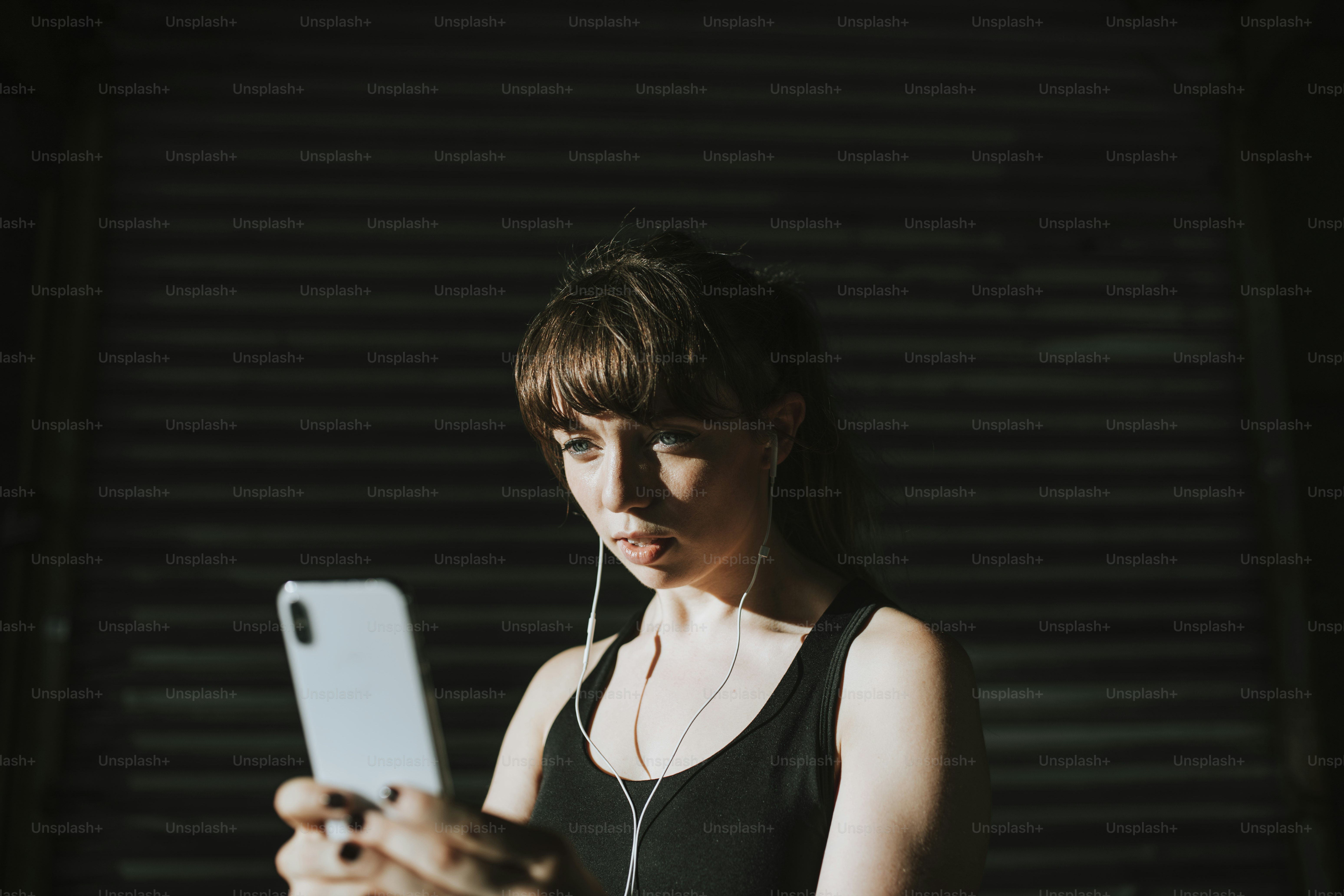 Sporty woman listening to music in a dark alley