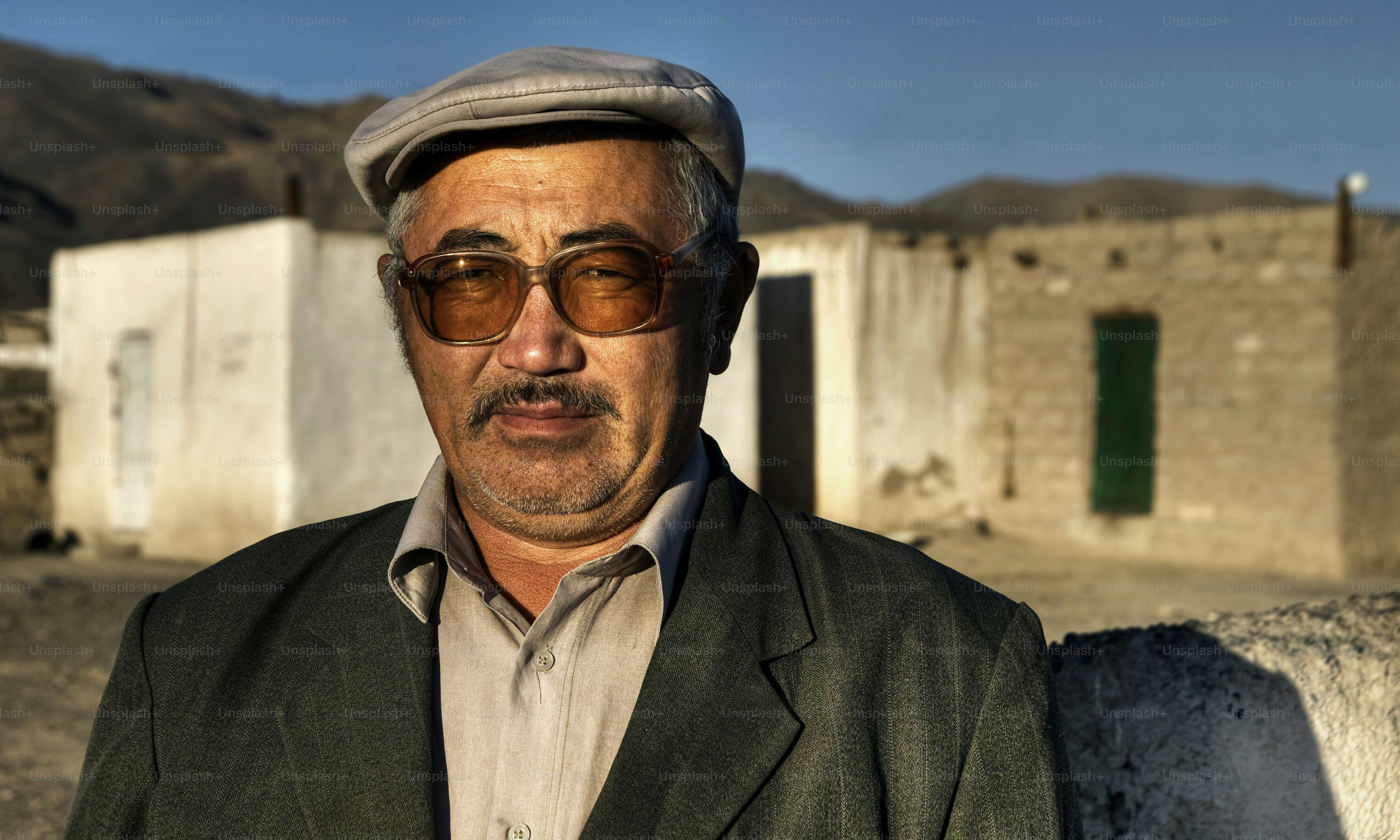Man wearing a cap and sunglasses in a rural setting.