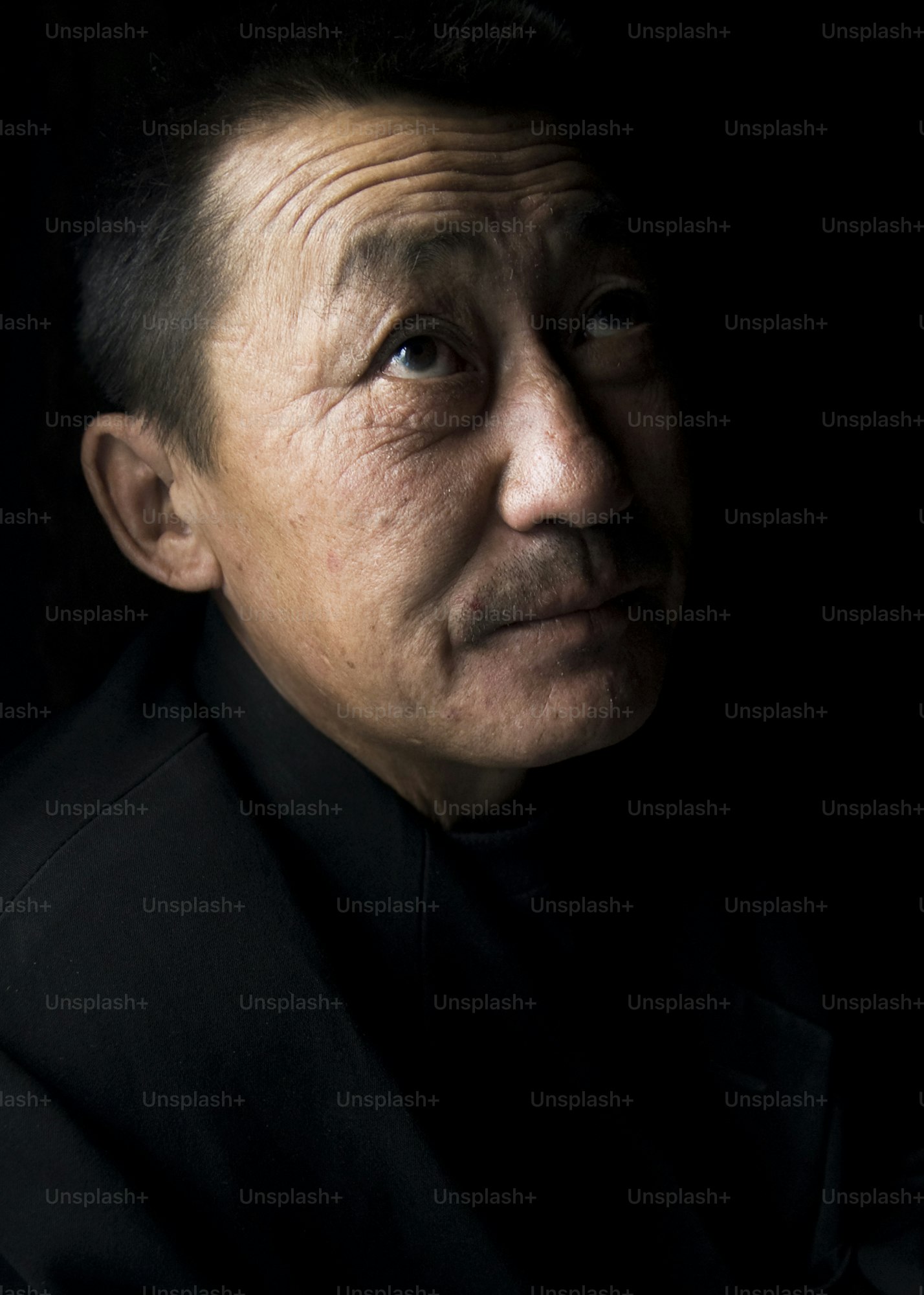An elderly man looks up with a thoughtful expression.