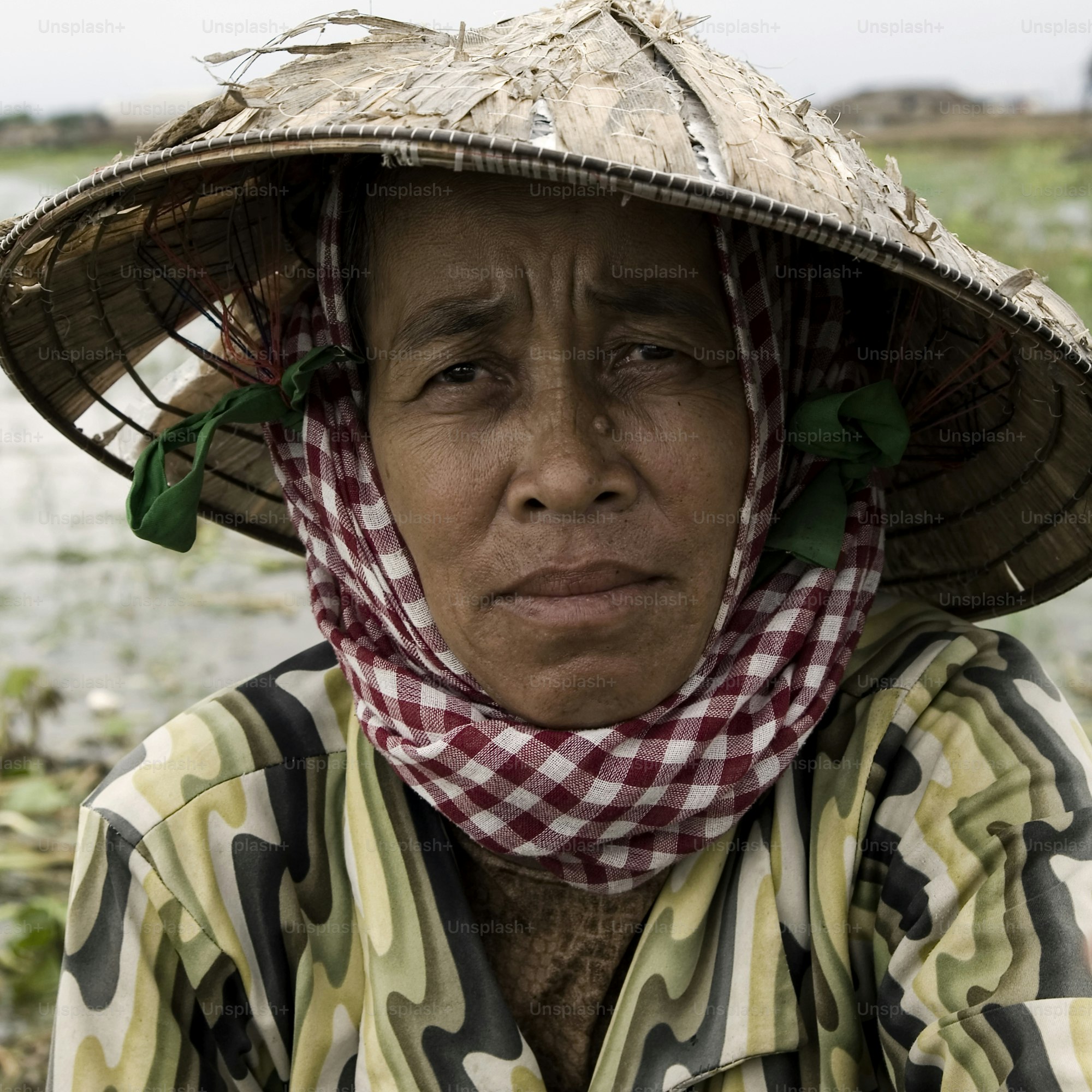 Woman wearing a conical hat and checkered scarf.