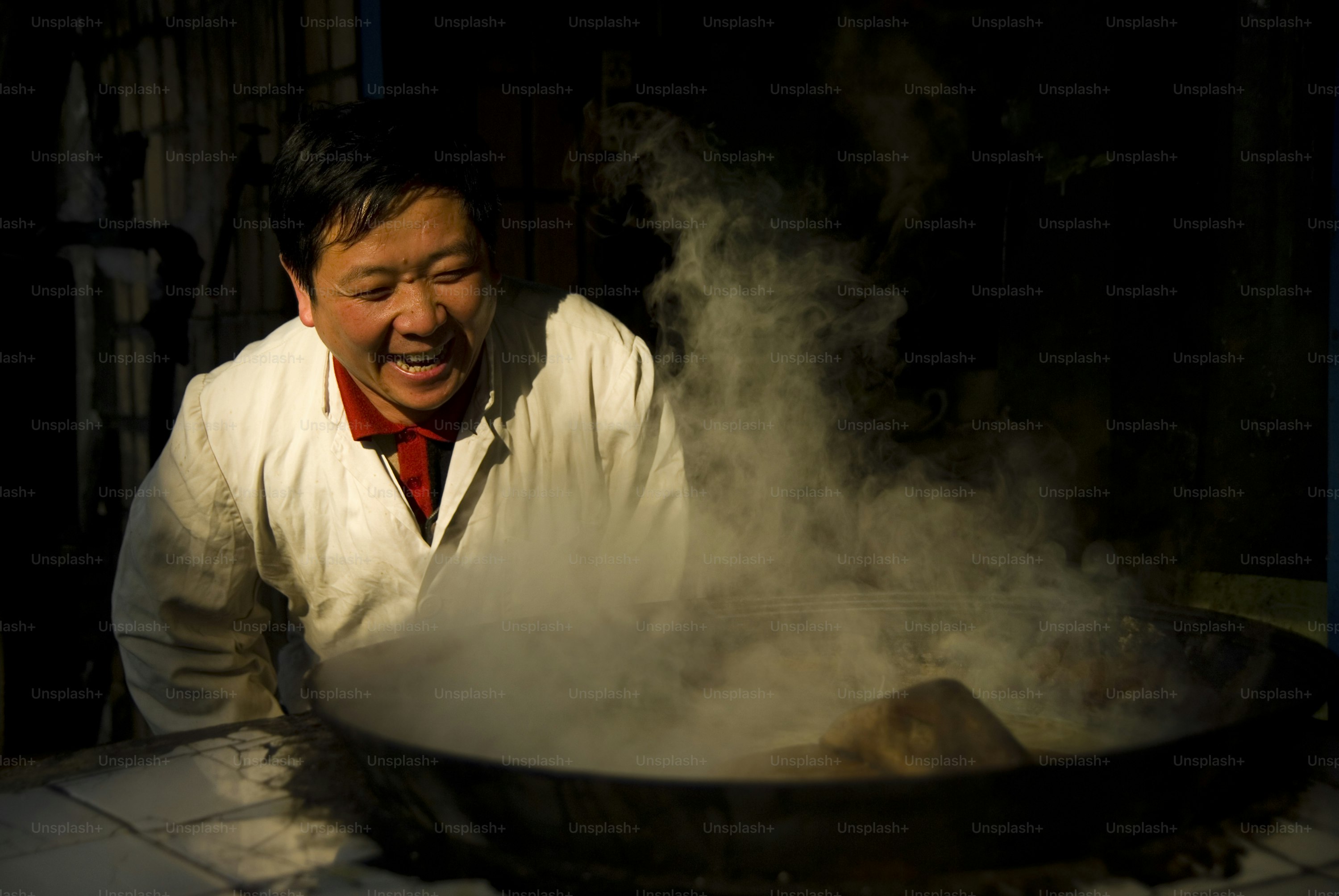 A man in a white coat cooking with steam