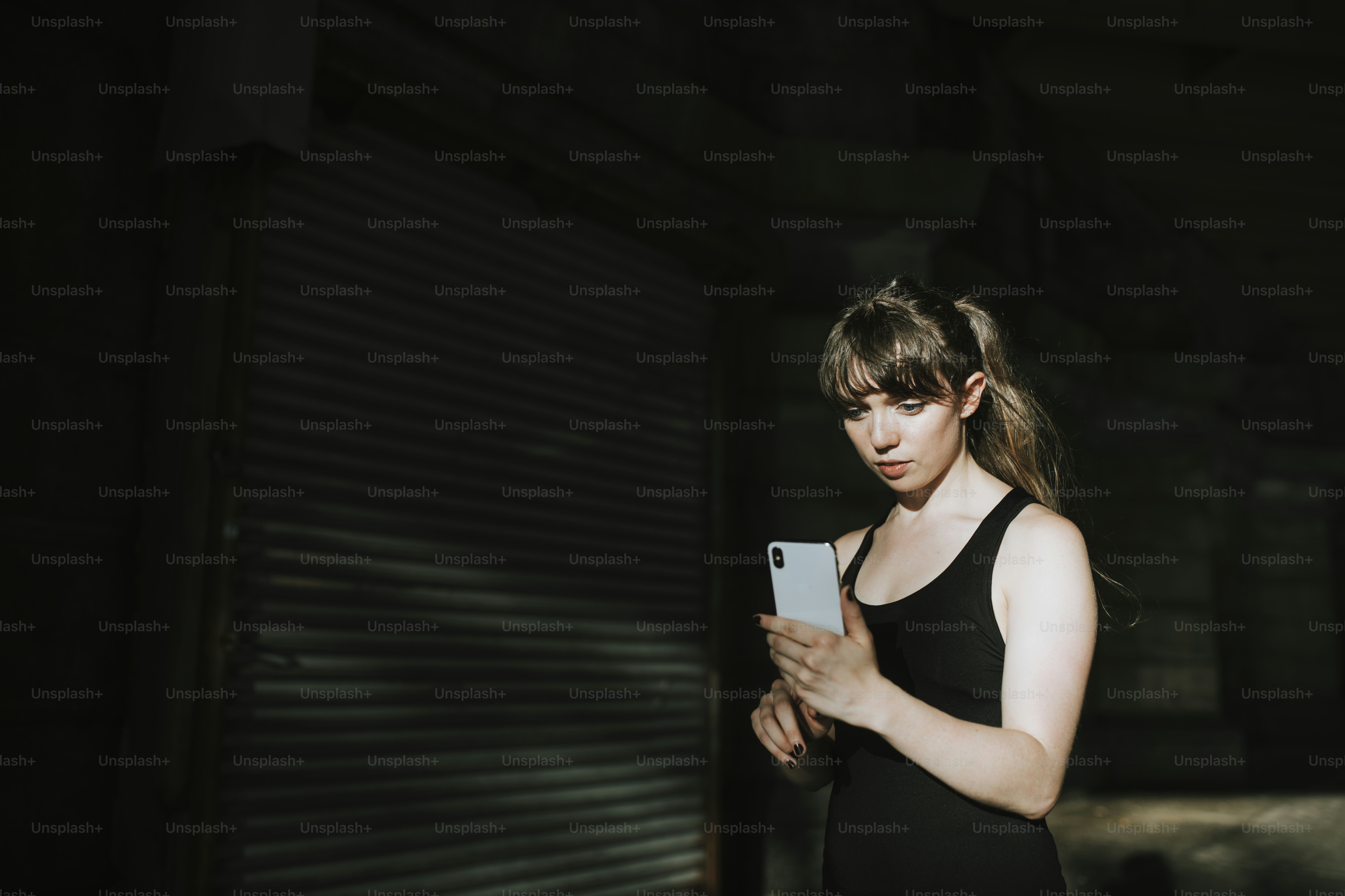 Sporty woman texting in a dark alley