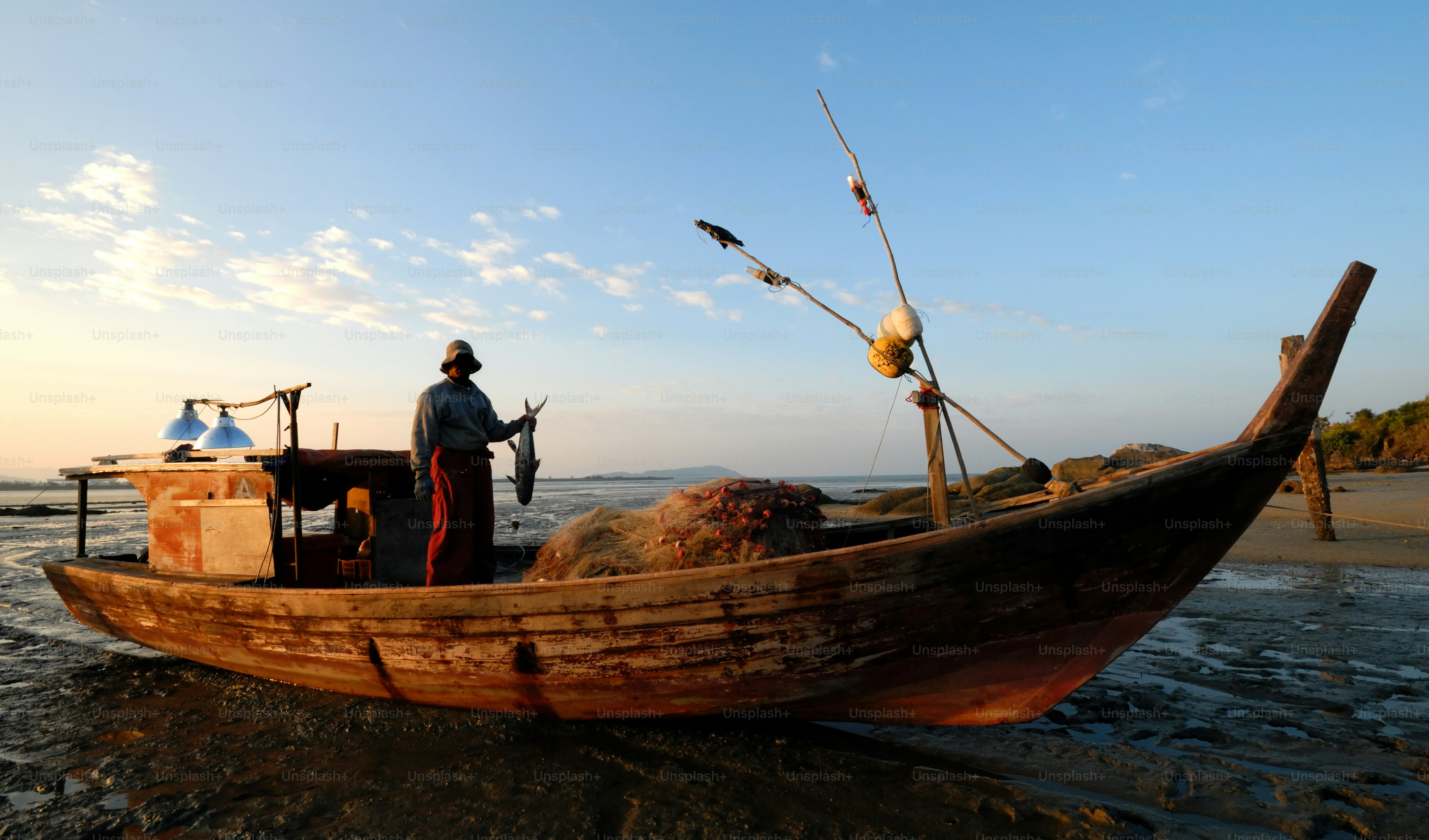 Nelayan dengan perahu di pantai saat matahari terbenam
