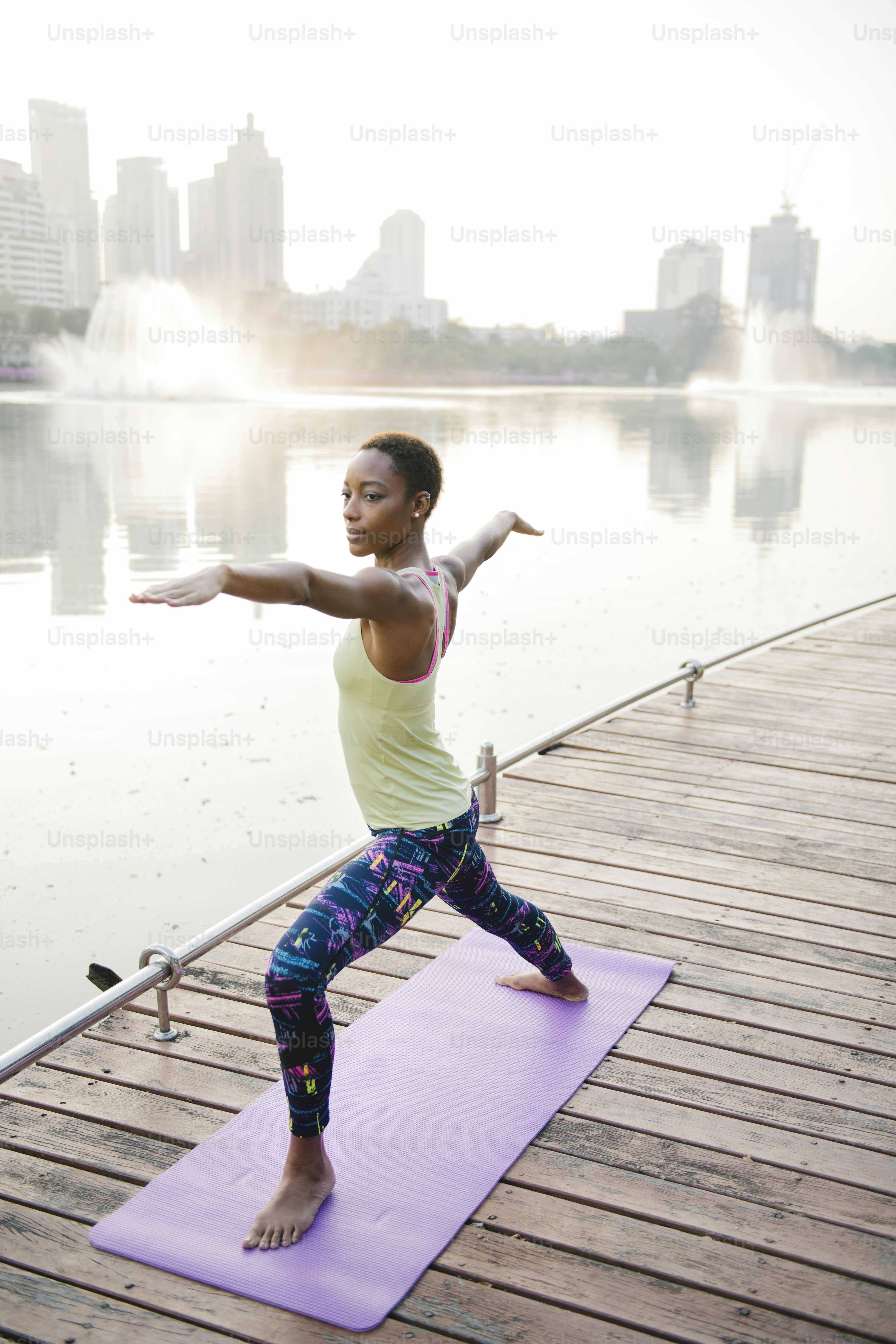 Black lady doing a virabhadrasana pose in a park