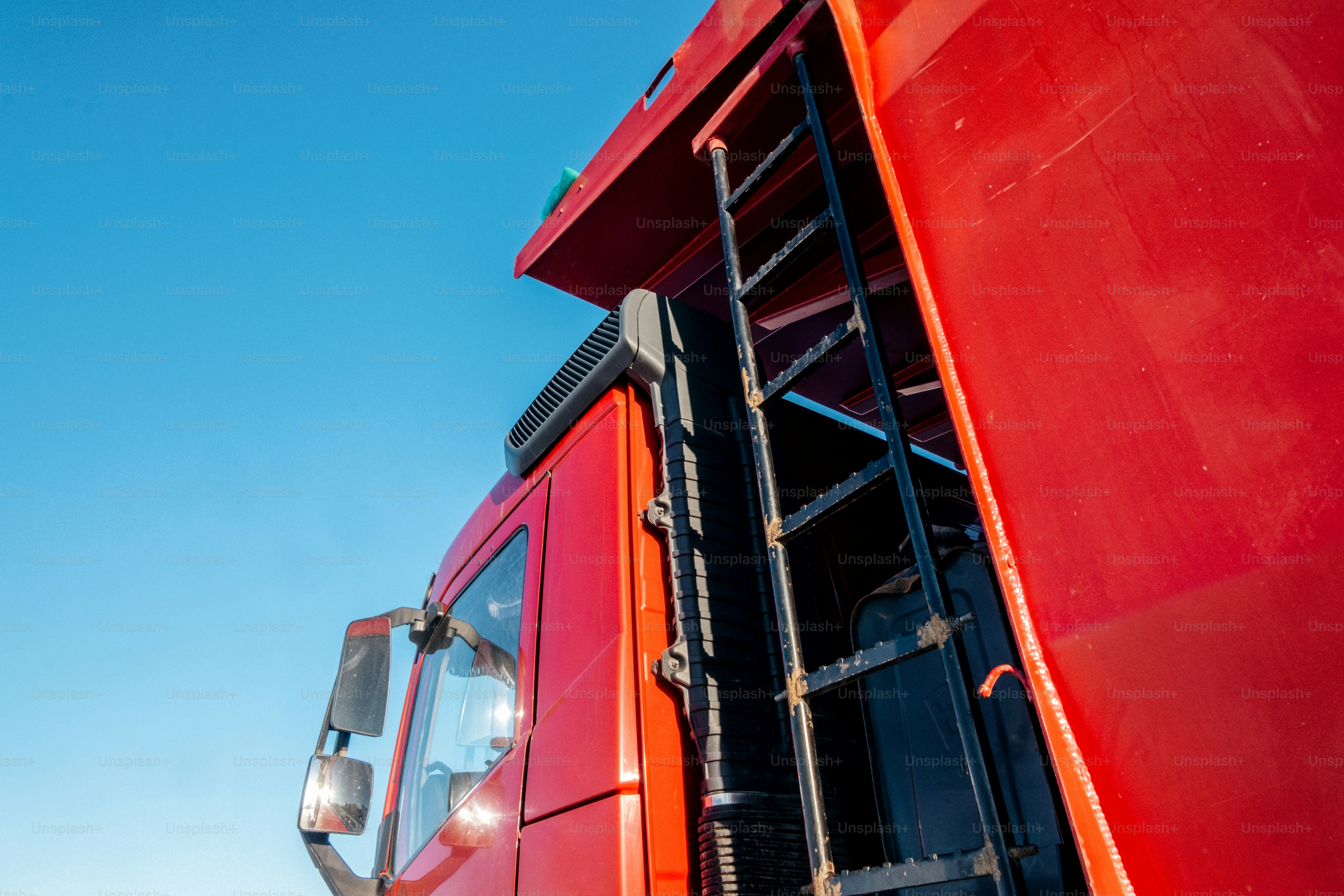 Red dump truck with ladder against blue sky