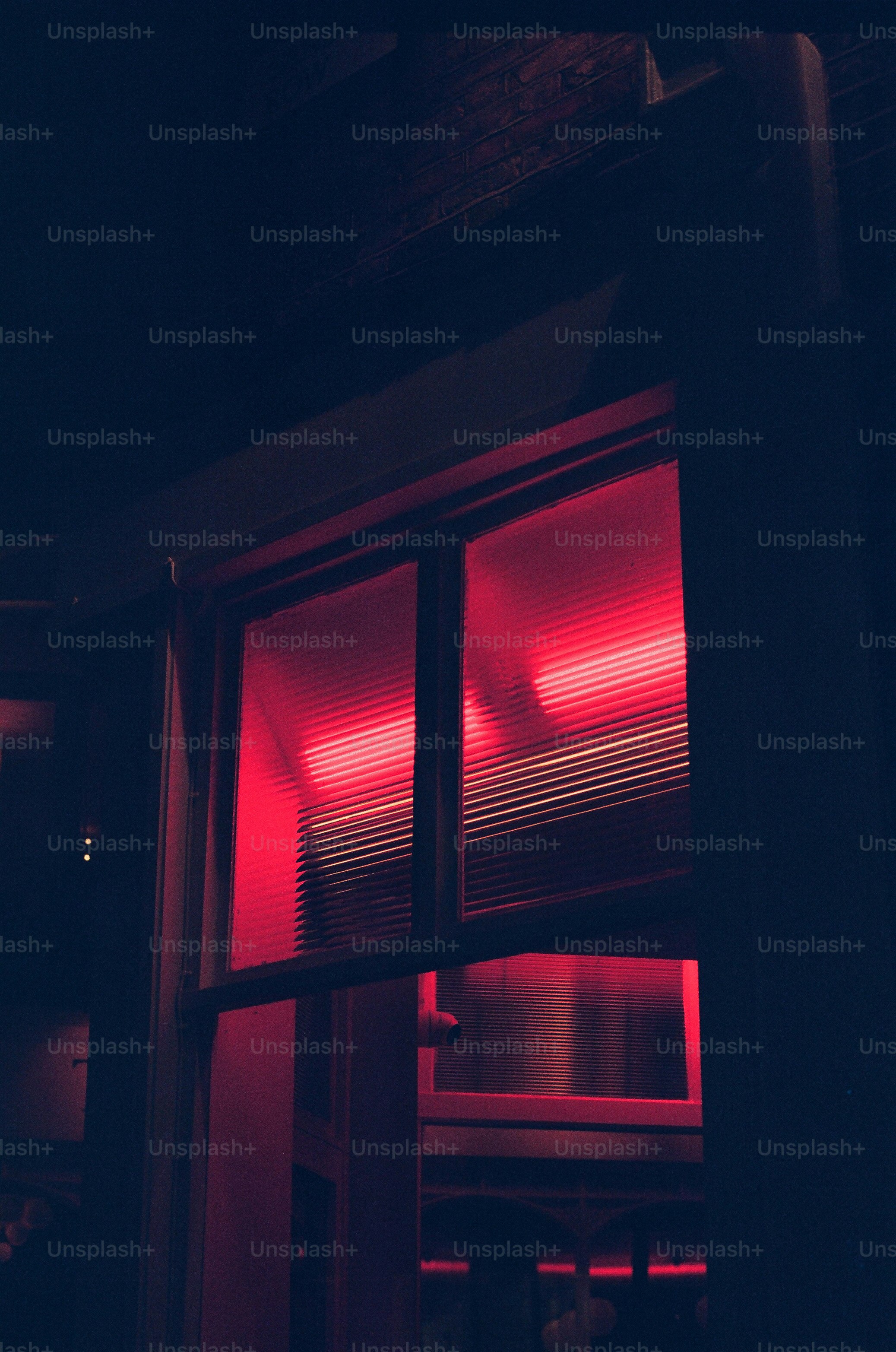A window glowing with red neon lights at night.