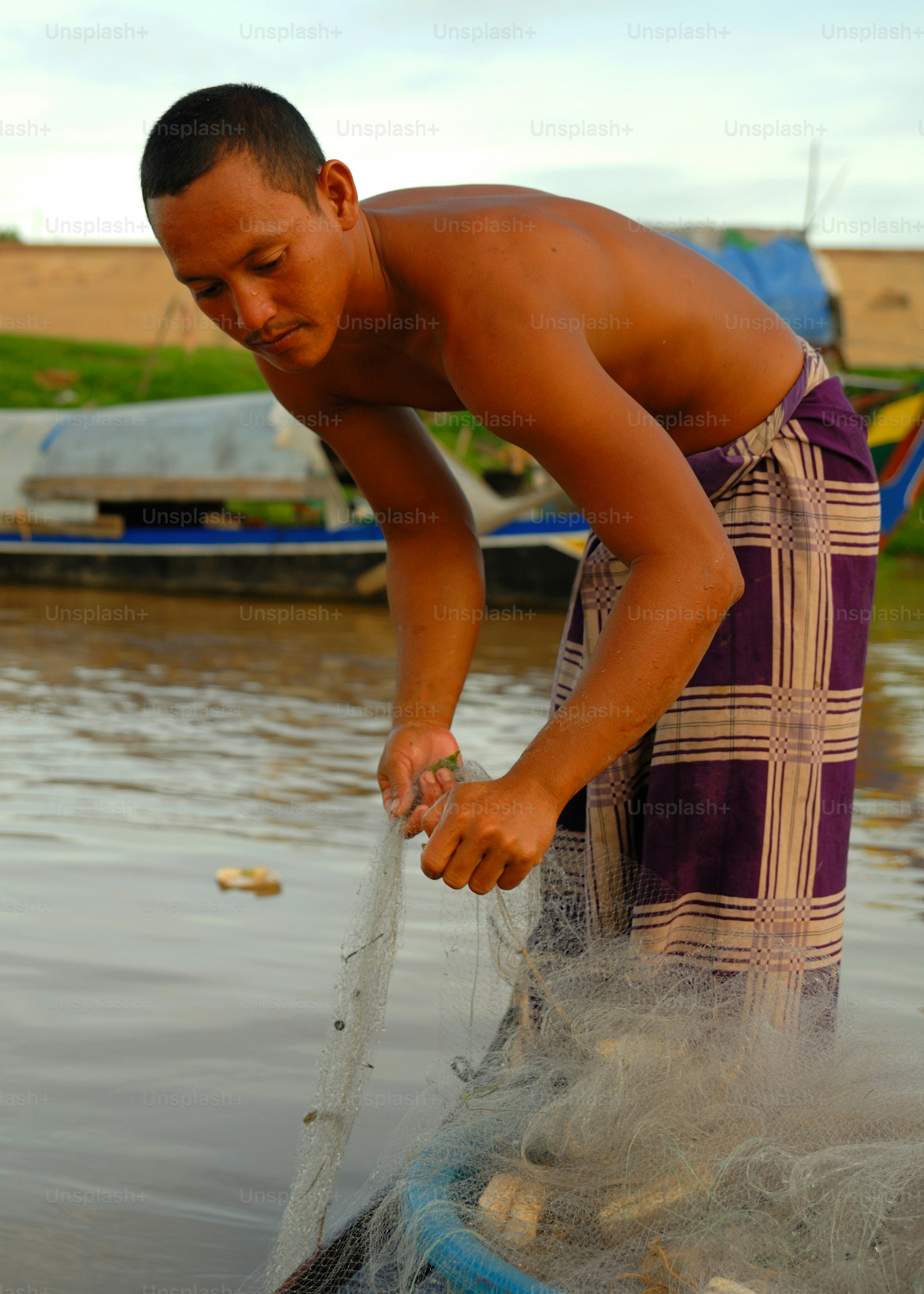 Asian Boatman checking his catch. Phnom Penh, Cambodia.