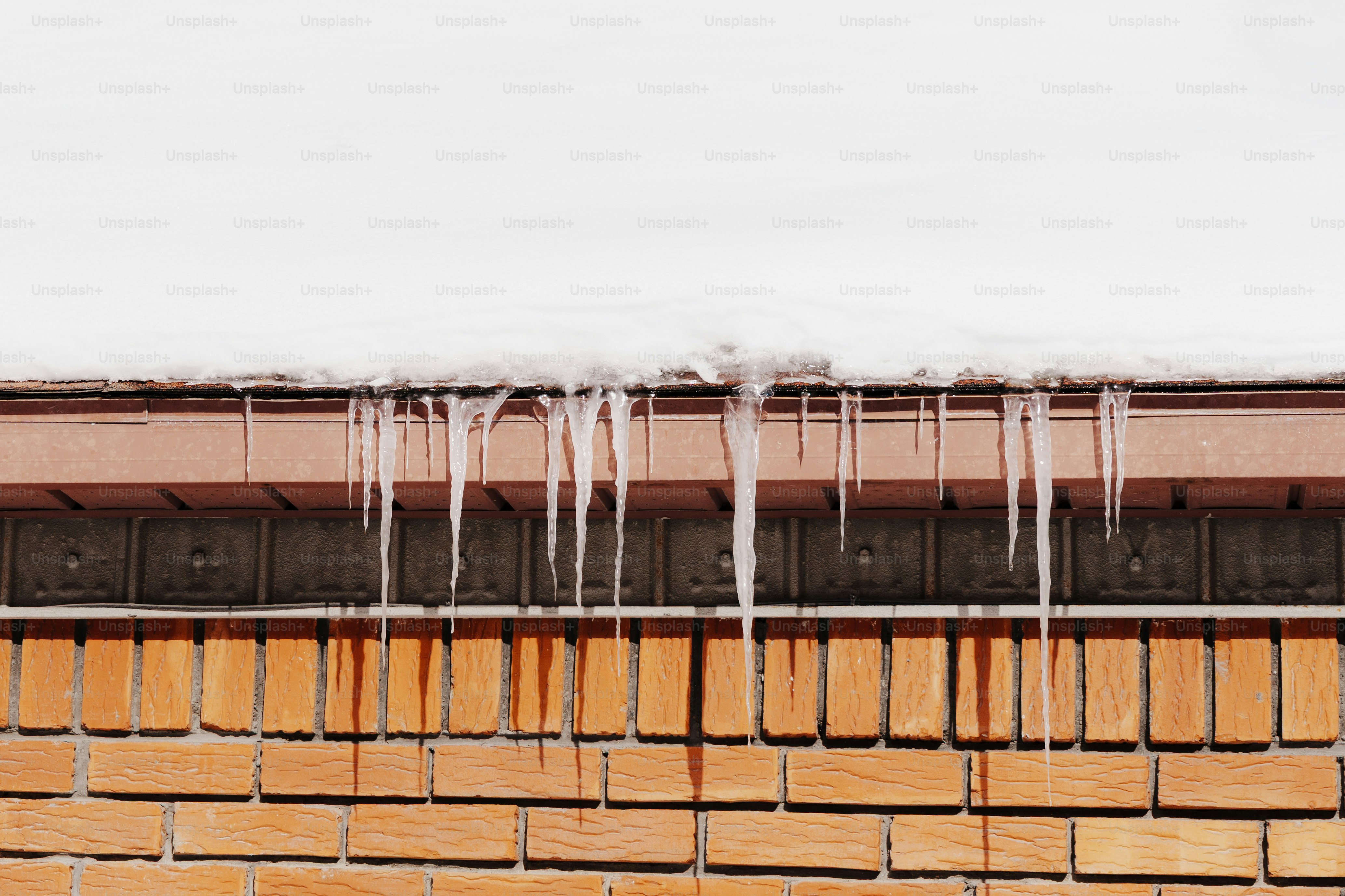 I ghiaccioli pendono dal bordo di un tetto coperto di neve.