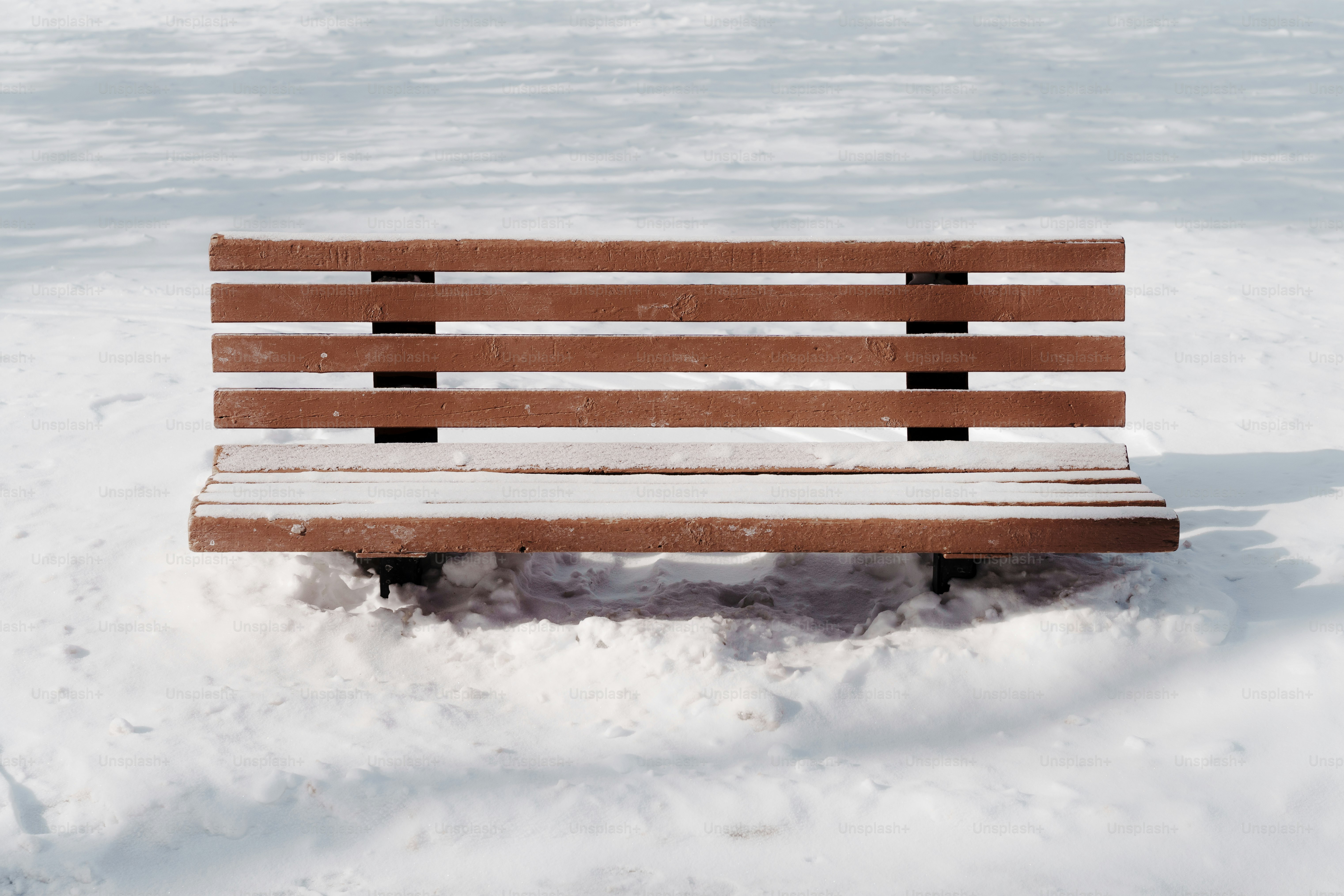 Um banco de madeira coberto de neve