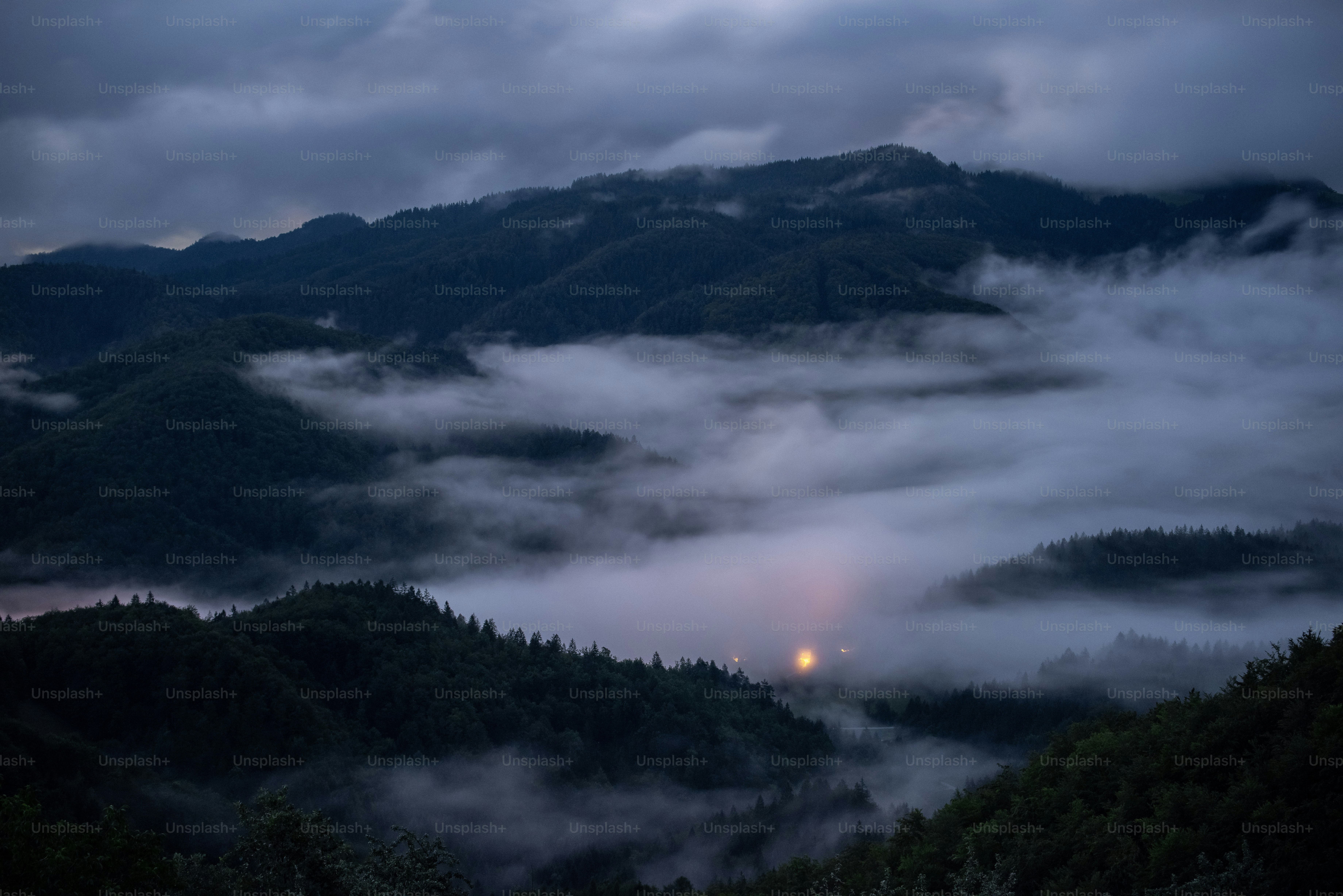 Montagnes brumeuses sous un ciel crépusculaire nuageux