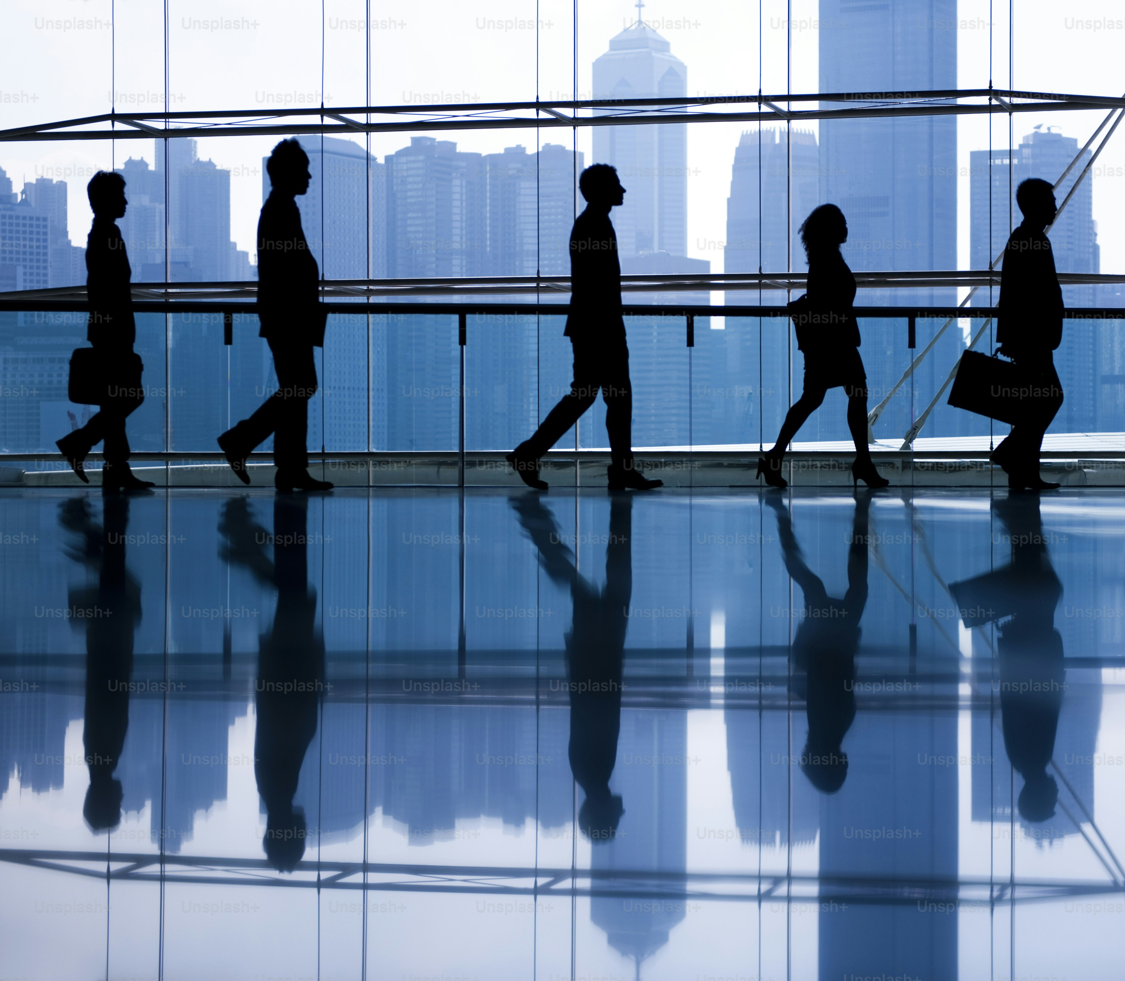 Silhouettes of business people walking in a modern office.